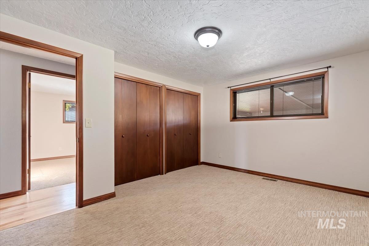 Unfurnished bedroom with carpet floors, multiple closets, and a textured ceiling