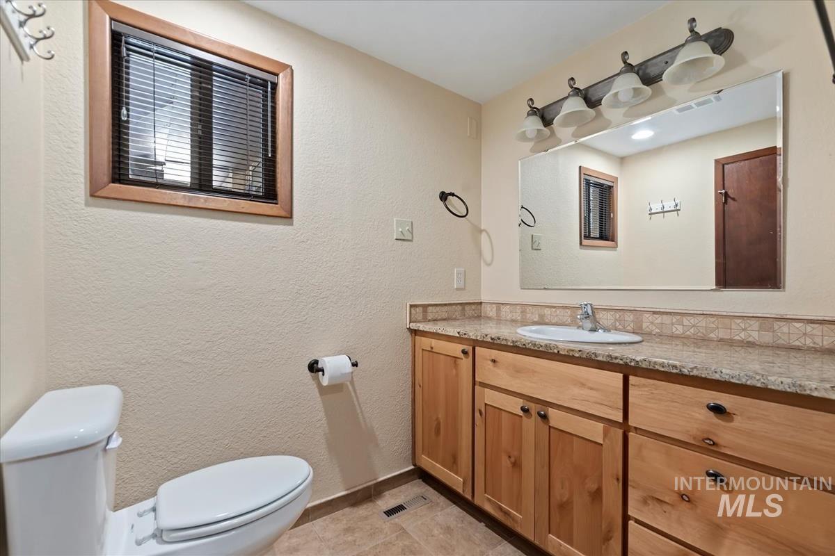 Bathroom with a textured wall, vanity, and light tile patterned floors