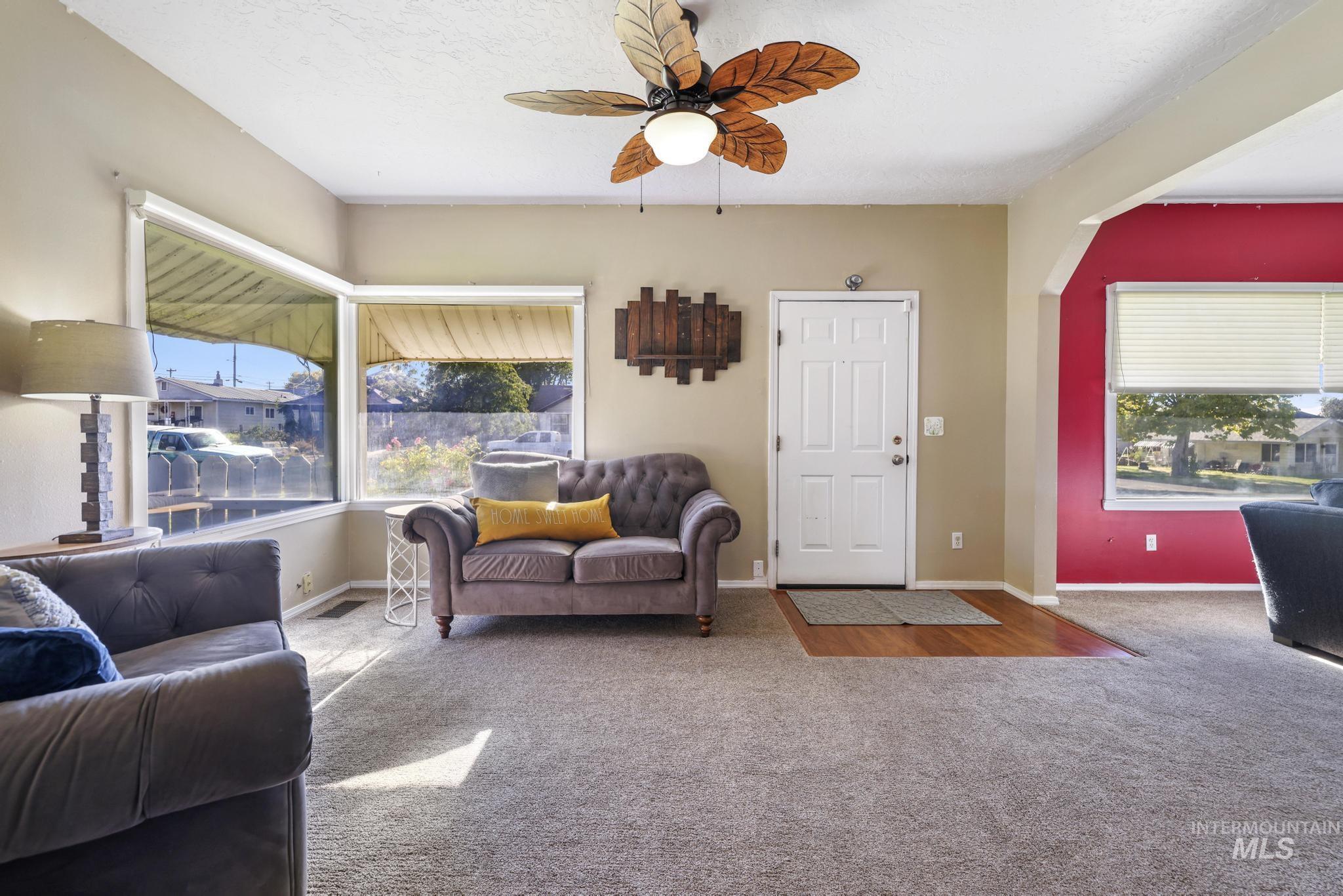Carpeted living area with a ceiling fan and a textured ceiling