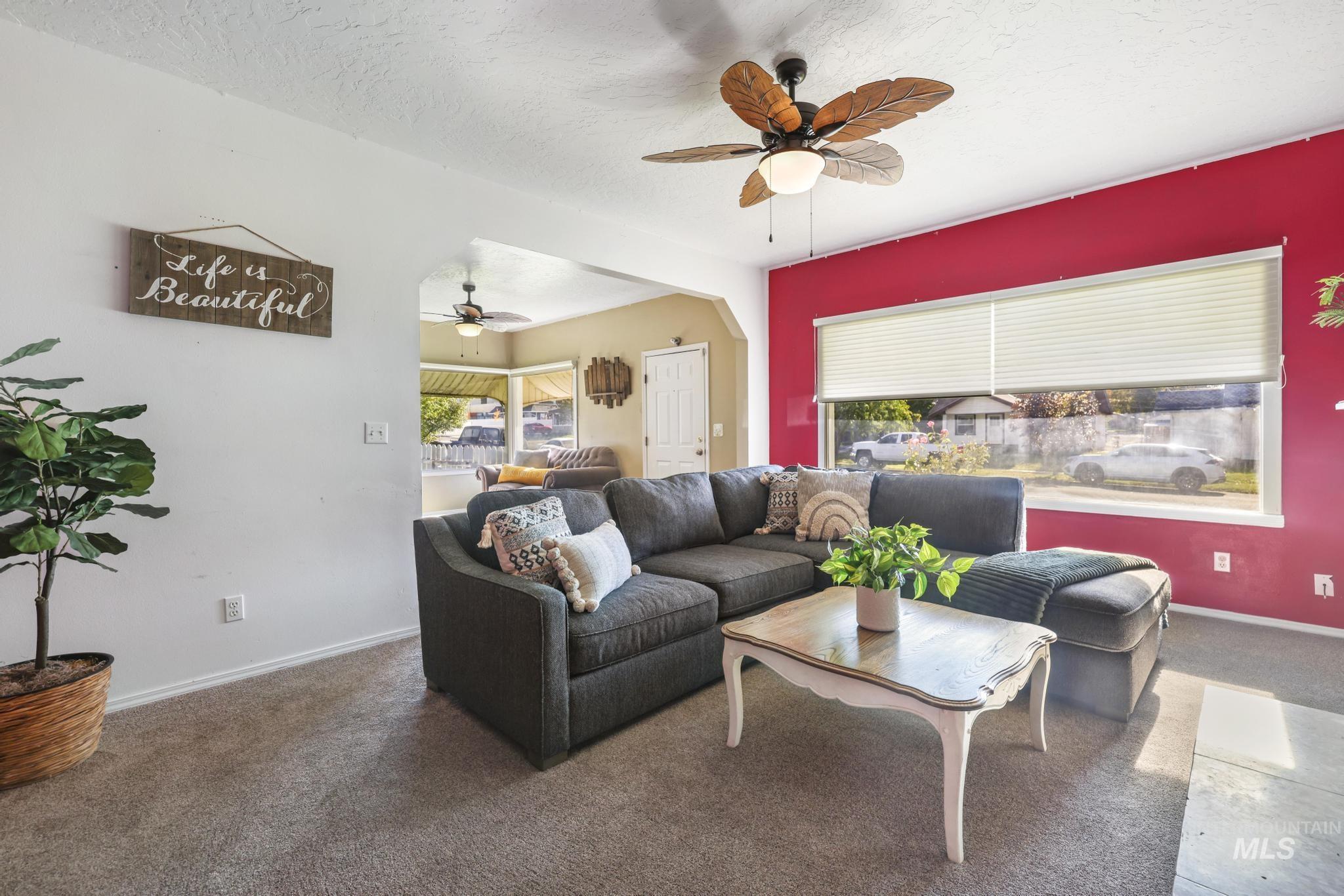 Living room with carpet floors, a textured ceiling, and ceiling fan