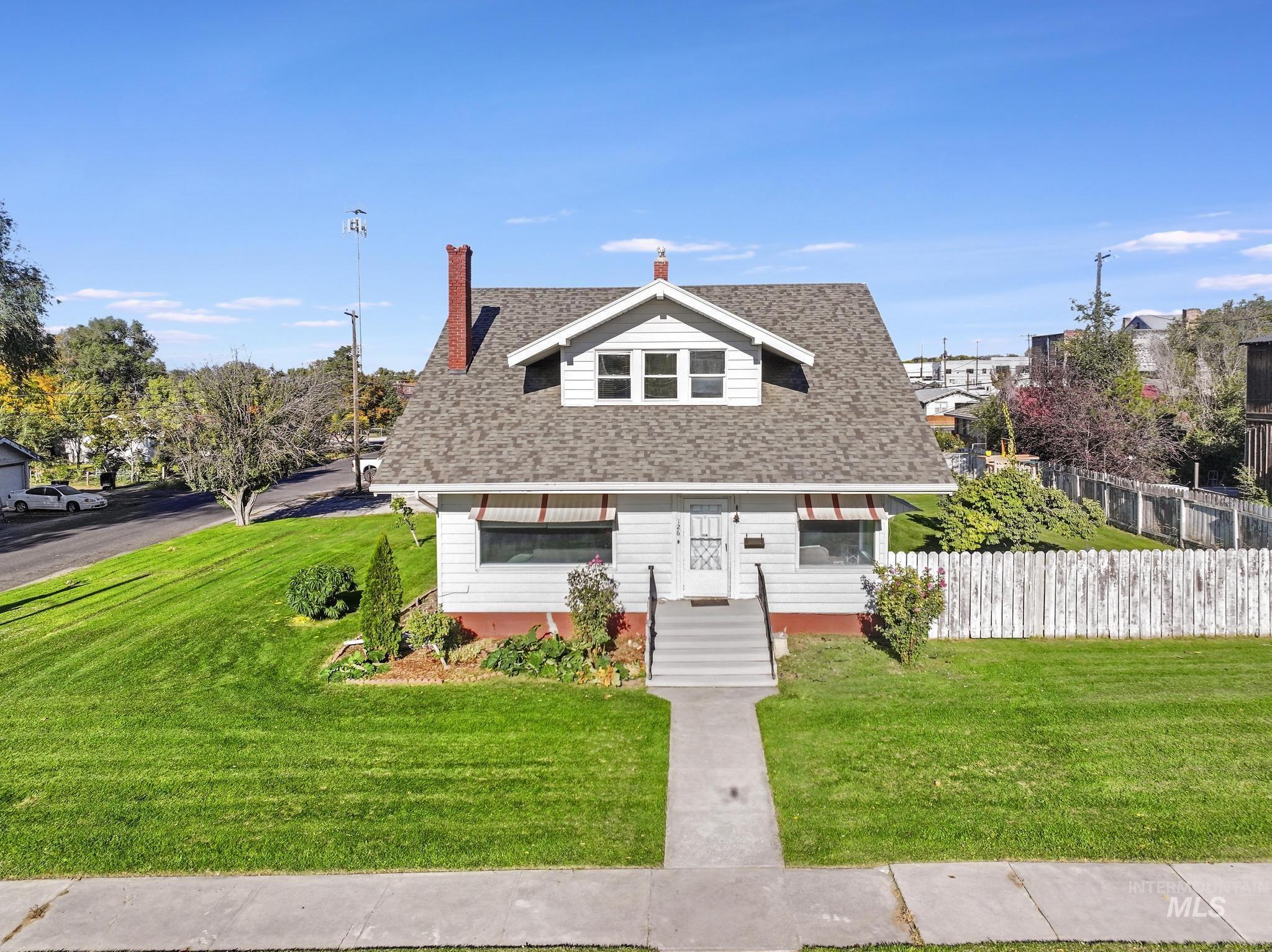 View of front of house with a shingled roof and a chimney