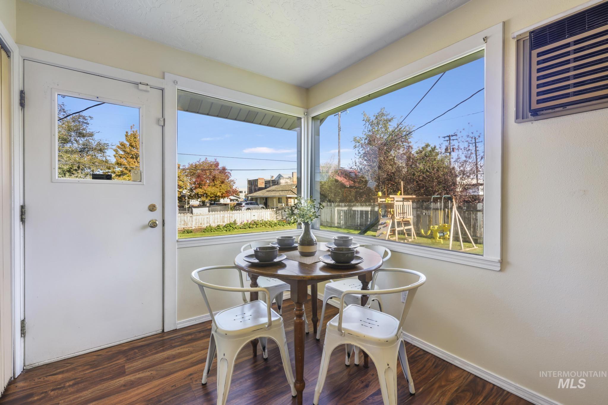 Dining area with dark wood-style flooring and a wall mounted AC