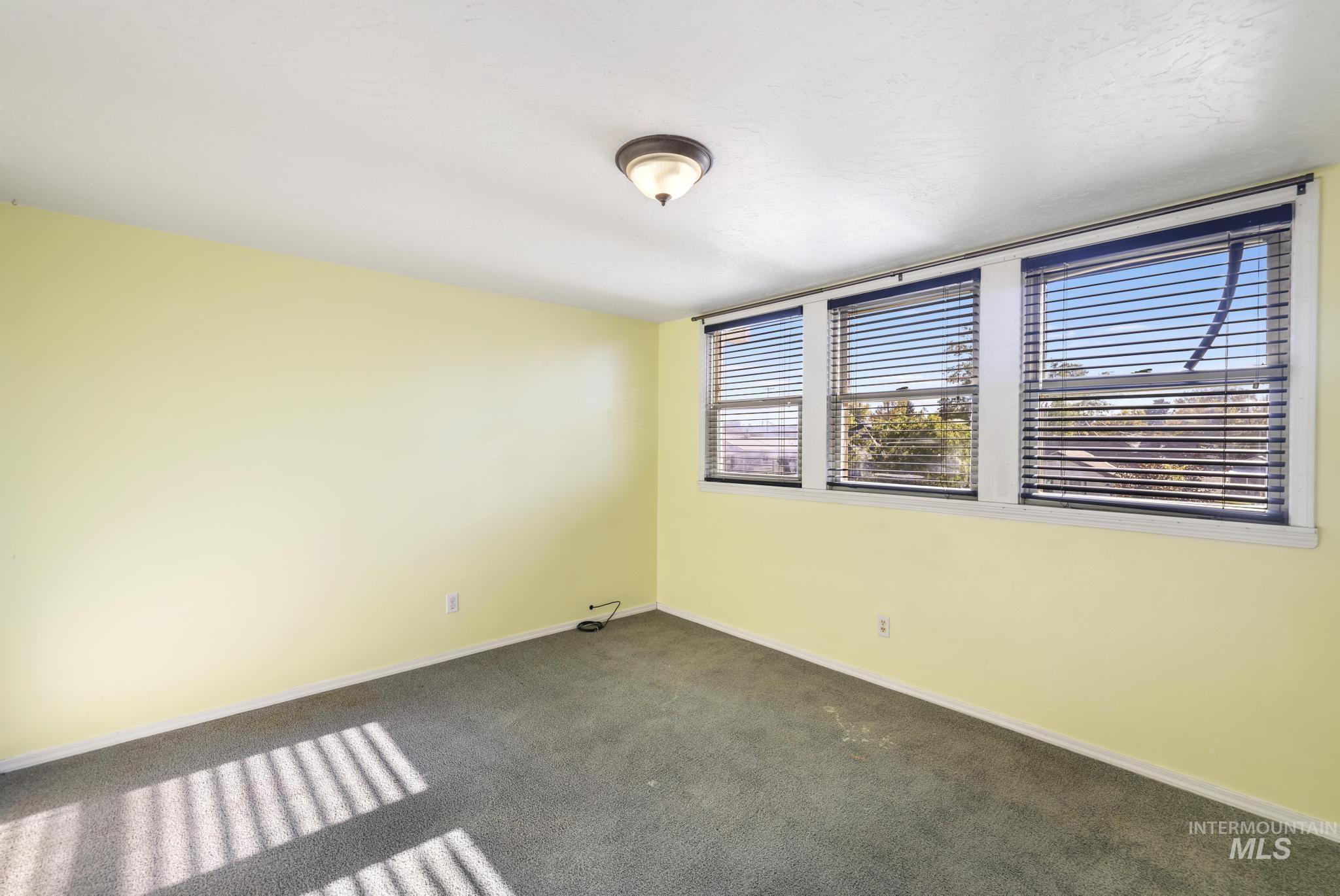 Spare room with dark carpet and baseboards