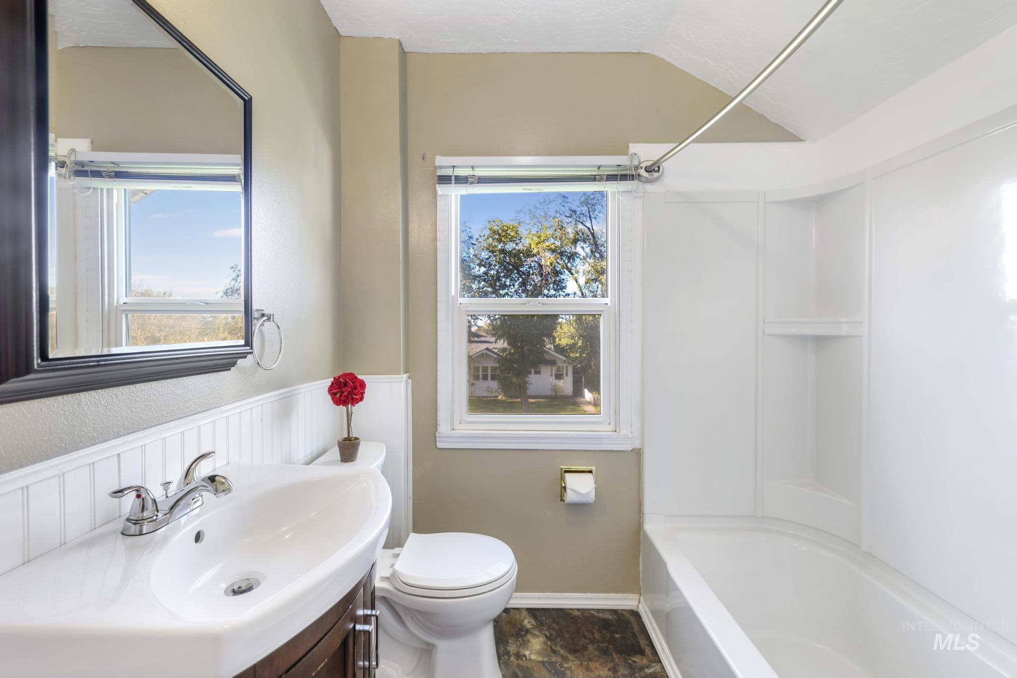 Bathroom featuring vanity, bathtub / shower combination, and lofted ceiling