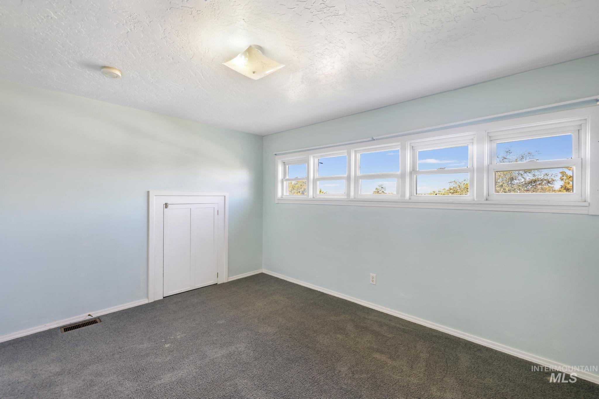 Unfurnished room featuring dark colored carpet and a textured ceiling