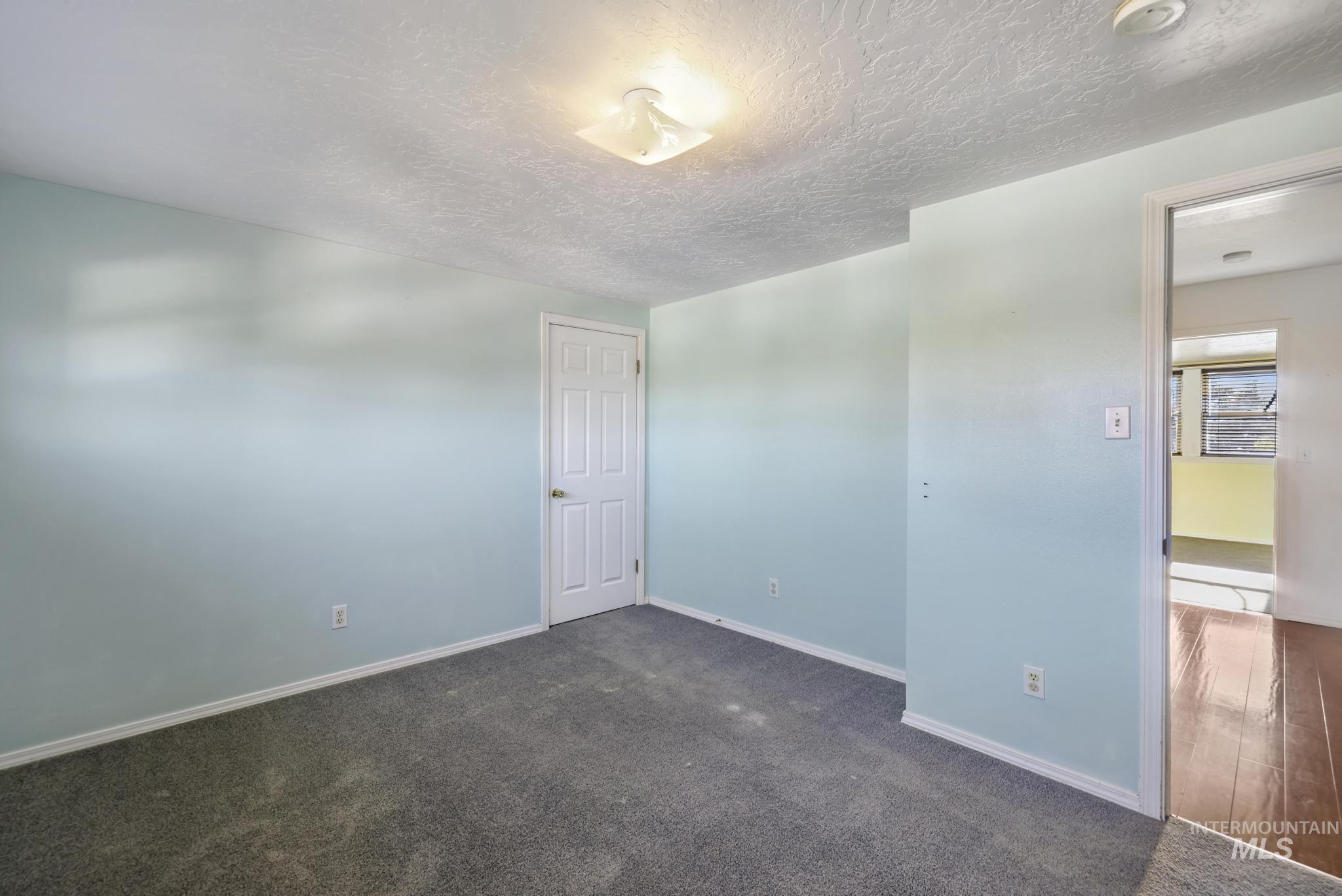Empty room with dark colored carpet and a textured ceiling