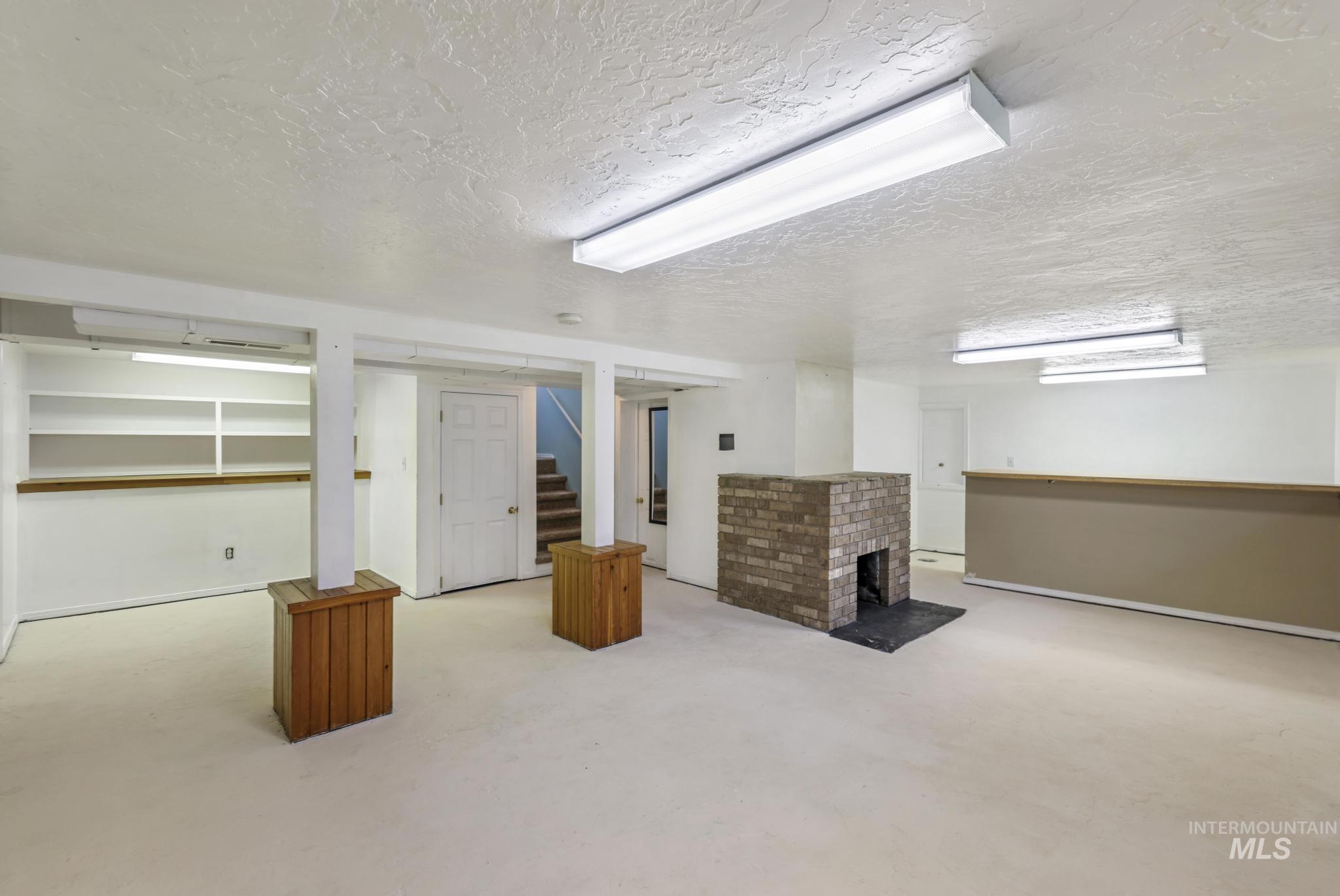 Finished below grade area featuring a fireplace, a textured ceiling, carpet, and stairway
