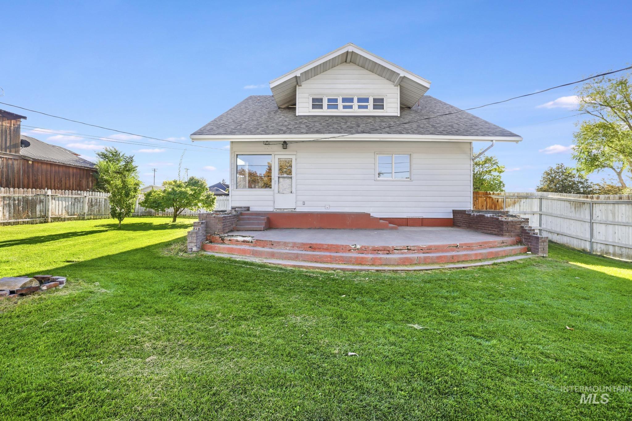 Rear view of house with a shingled roof and a fenced backyard