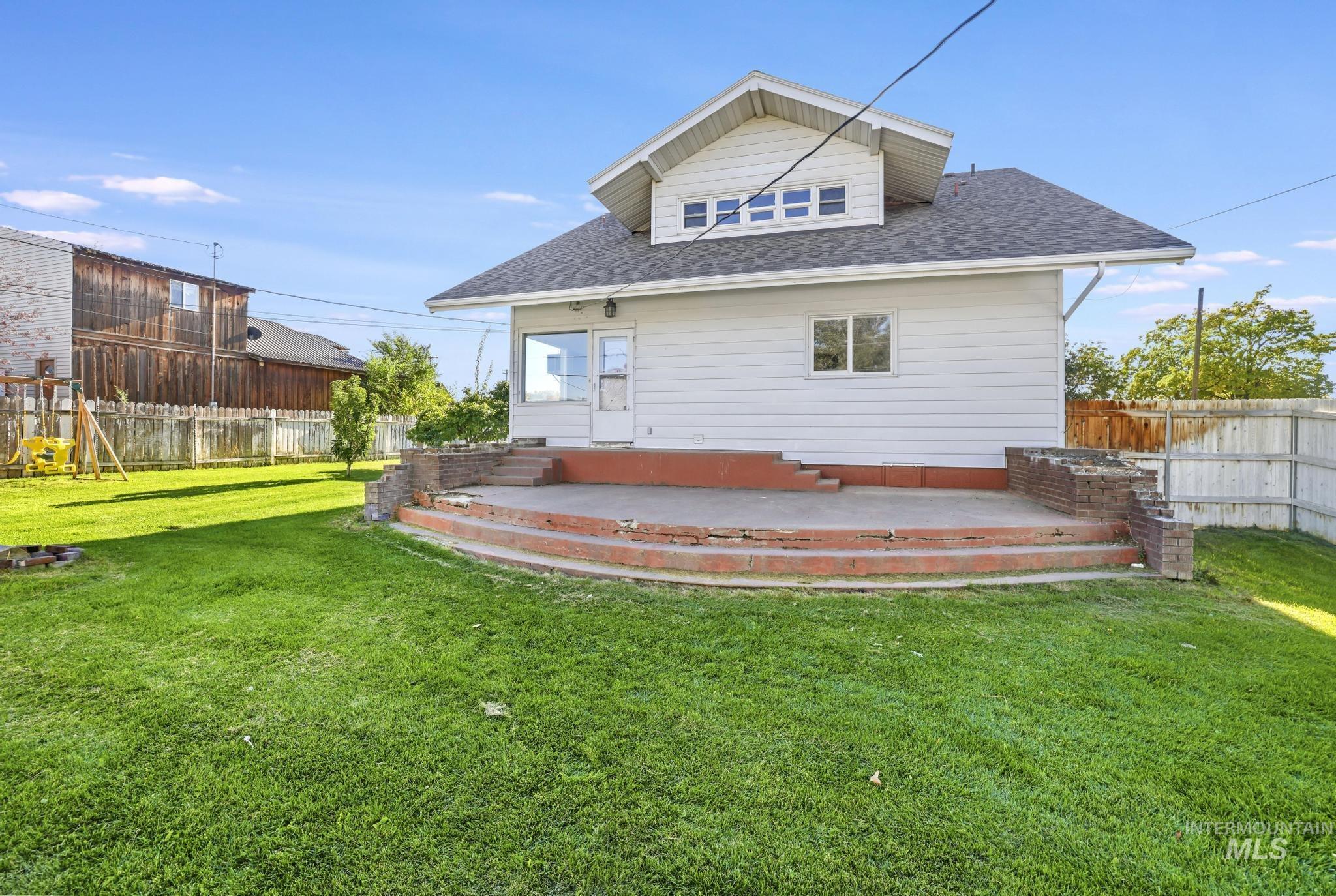 Back of house featuring a shingled roof, a fenced backyard, a patio, and a playground
