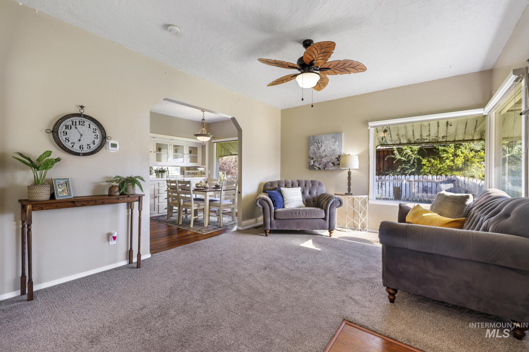 Living room with carpet flooring, healthy amount of natural light, a ceiling fan, and a textured ceiling