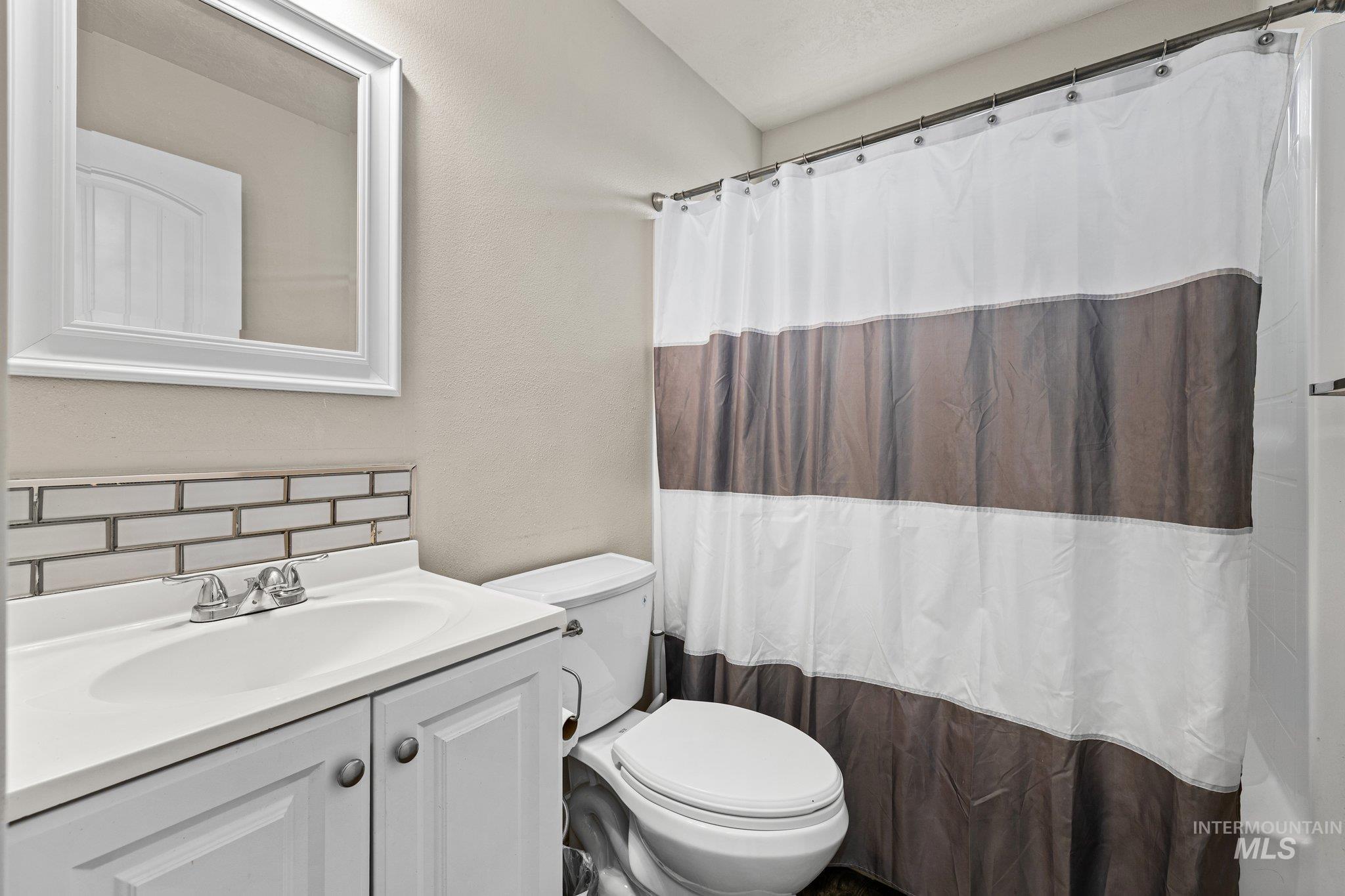 Bathroom with vanity, decorative backsplash, and curtained shower