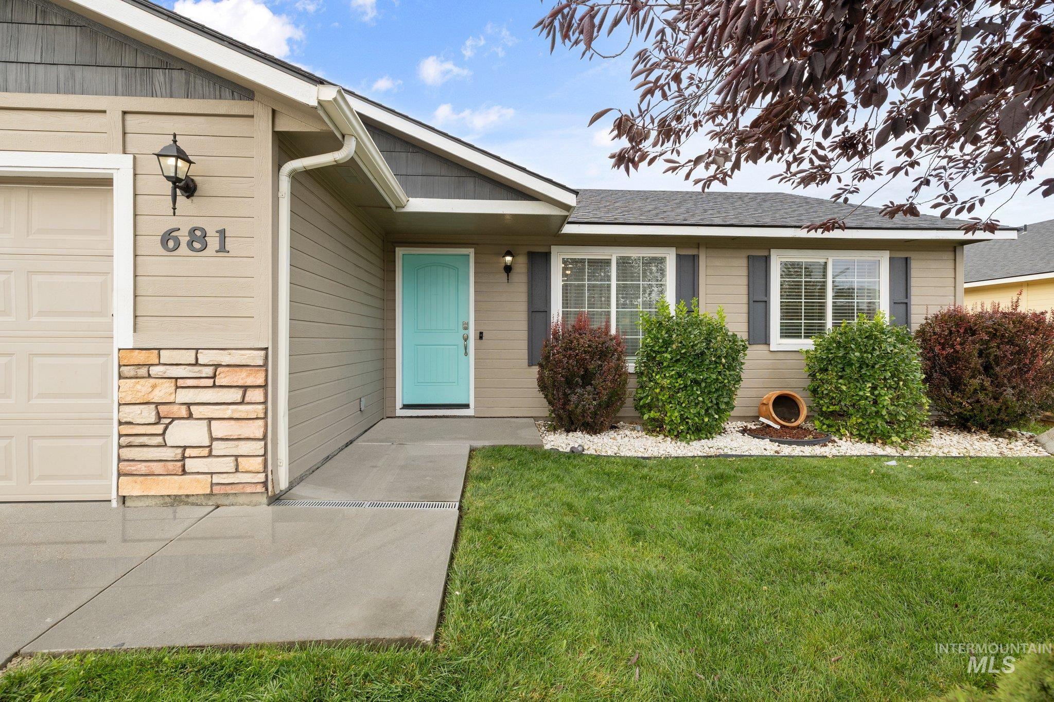 Property entrance featuring stone siding, a lawn, a shingled roof, and a garage
