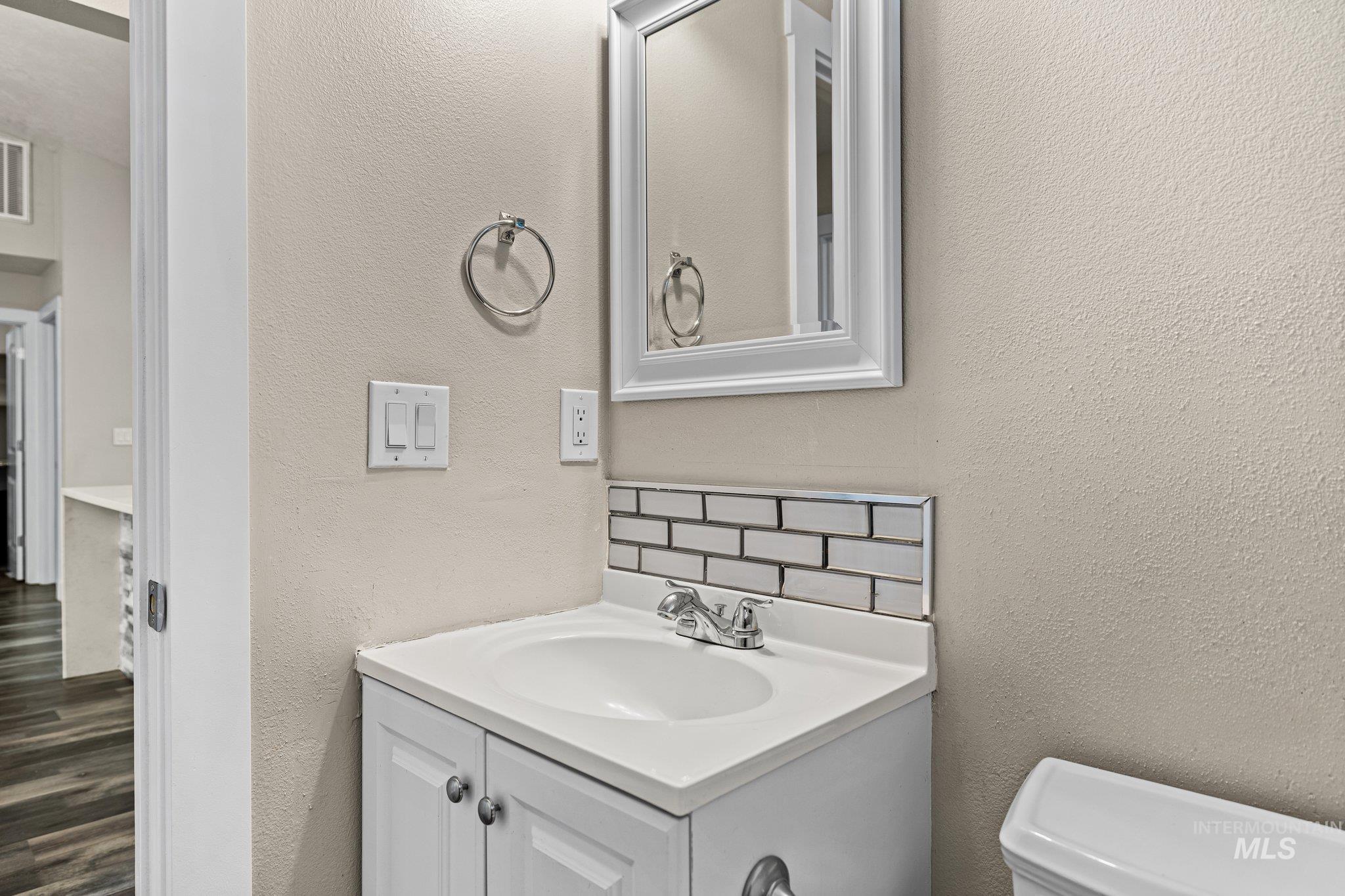 Half bathroom with a textured wall and vanity
