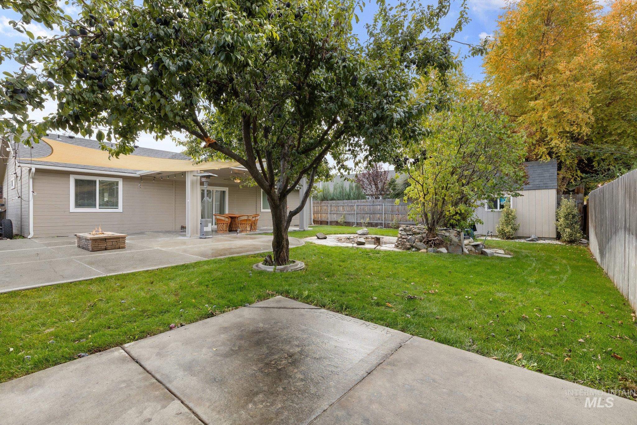 Fenced backyard with an outdoor fire pit, a patio area, and a storage shed