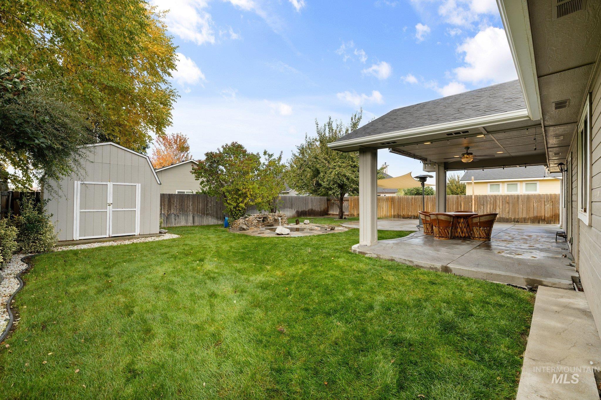 Fenced backyard featuring a patio, a shed, and ceiling fan