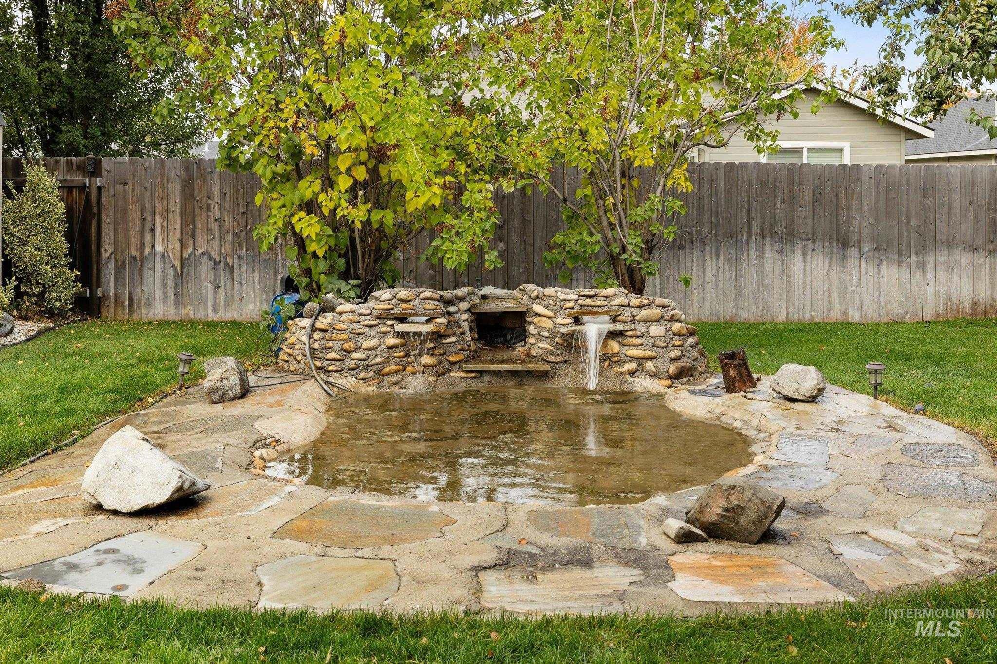 Fenced backyard featuring a patio area and a garden pond