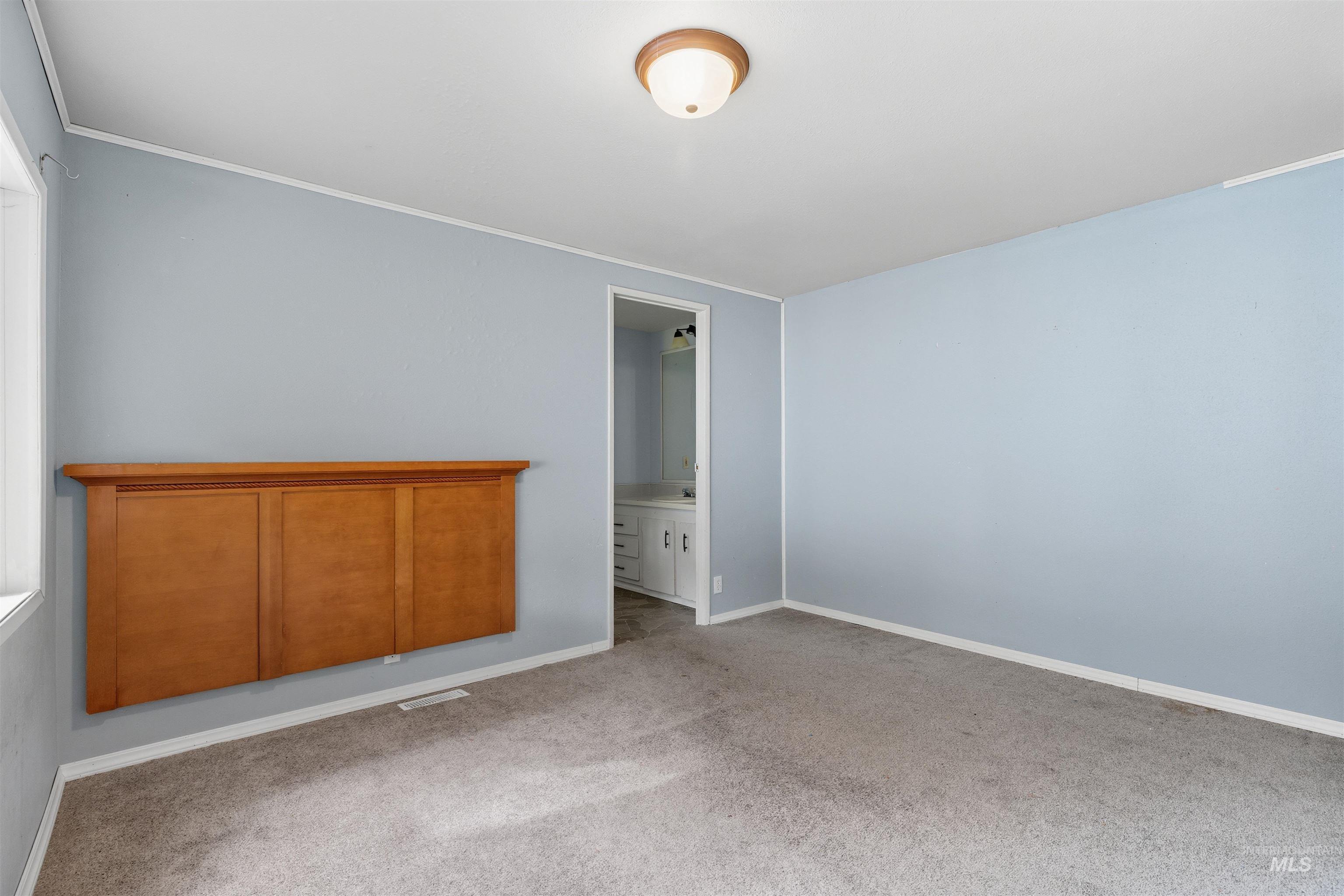 Unfurnished bedroom featuring carpet, ensuite bath, and ornamental molding