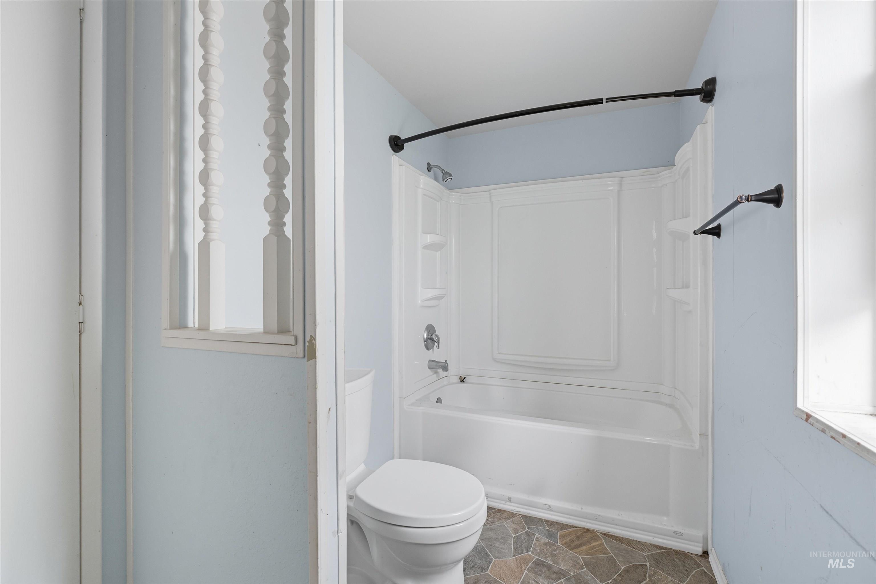 Bathroom featuring bathtub / shower combination and stone finish floors
