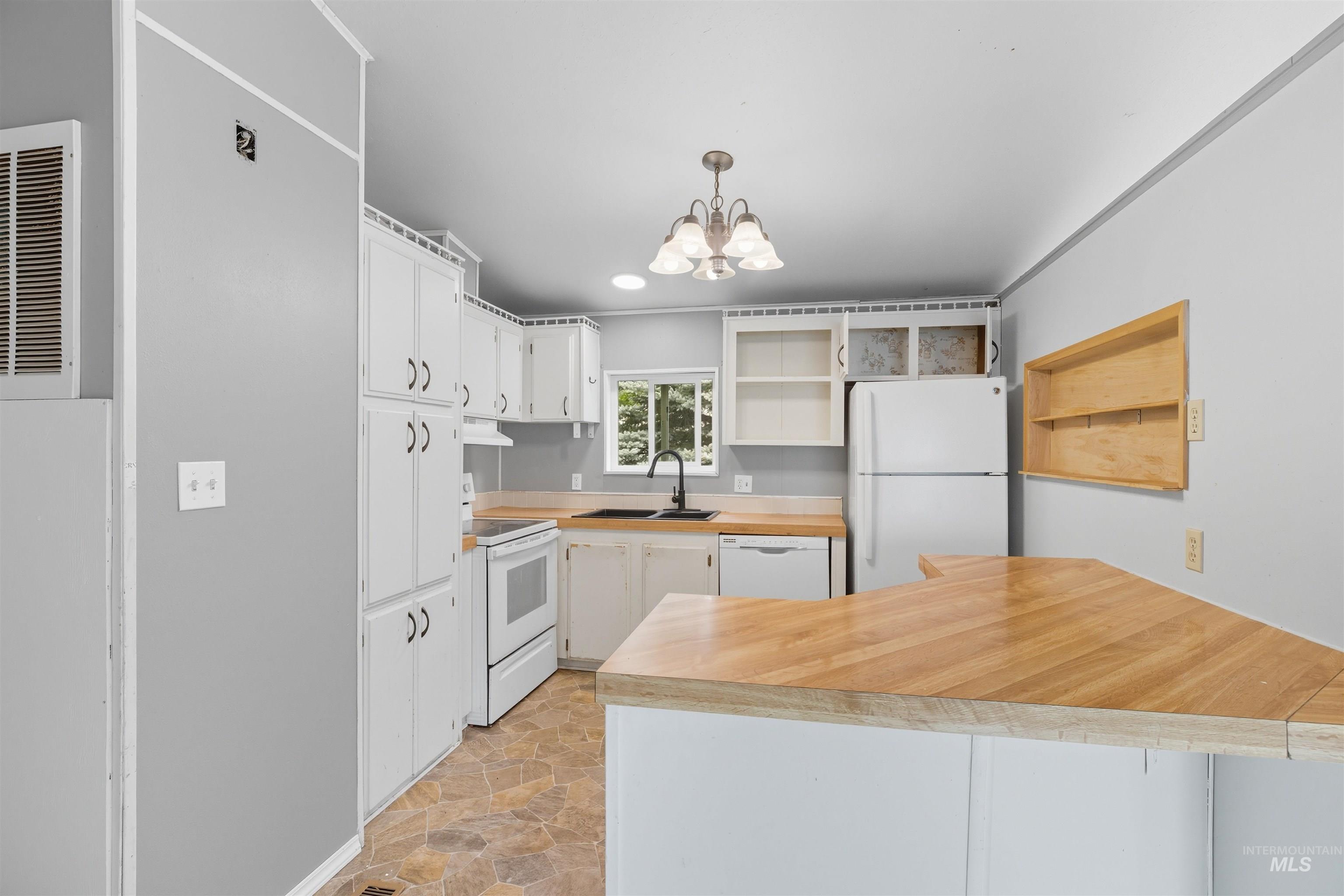 Kitchen with open shelves, white appliances, light countertops, stone finish flooring, and white cabinets
