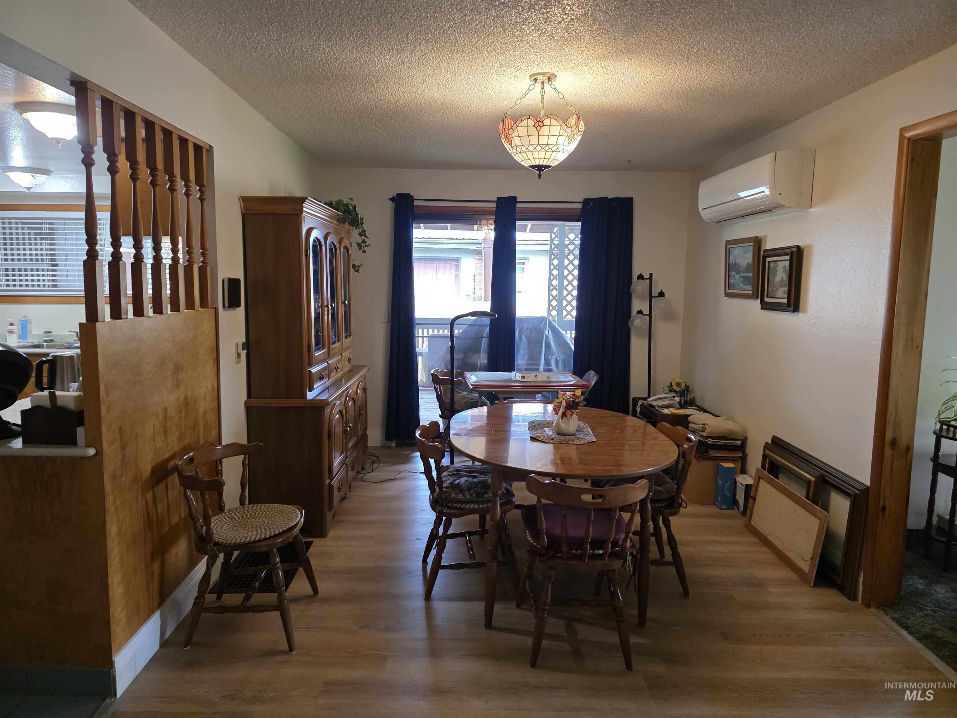 Dining room featuring wood finished floors, a textured ceiling, and an AC wall unit