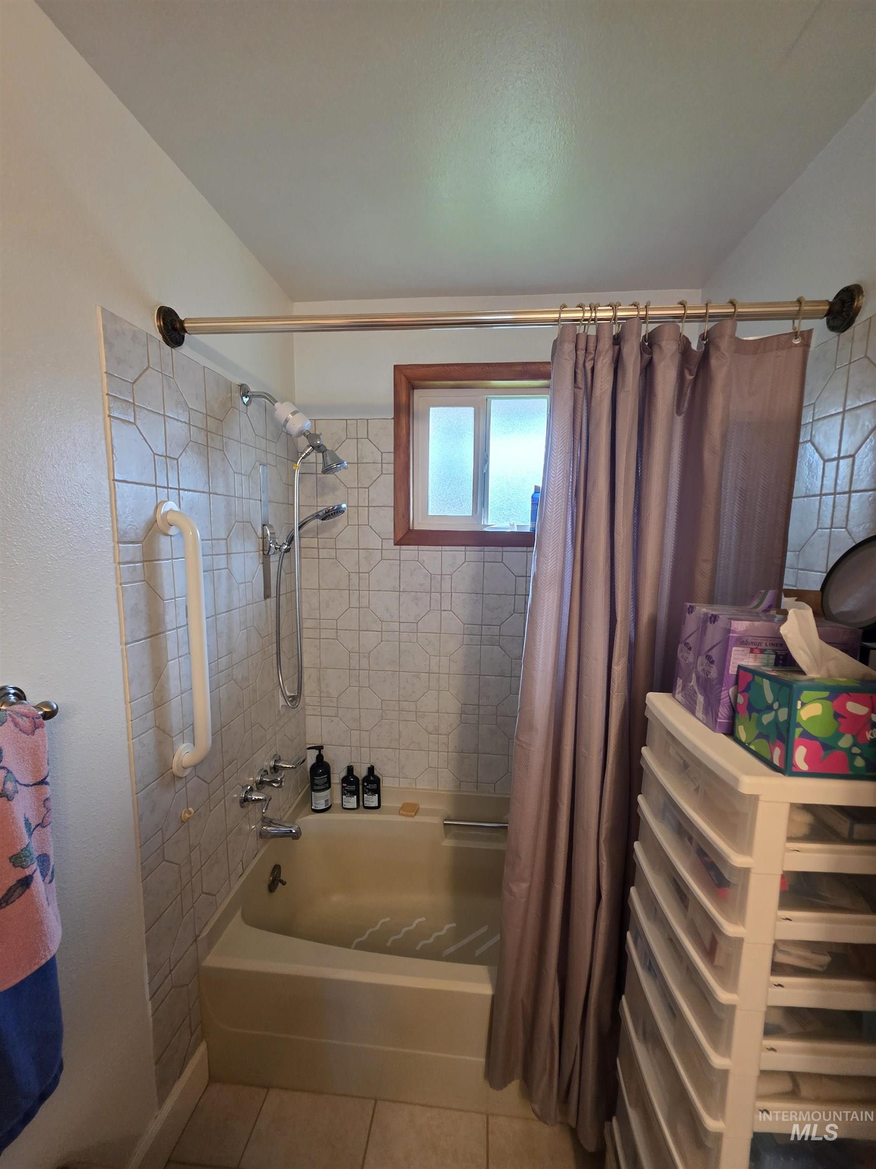 Bathroom with shower / bath combo with shower curtain and light tile patterned floors