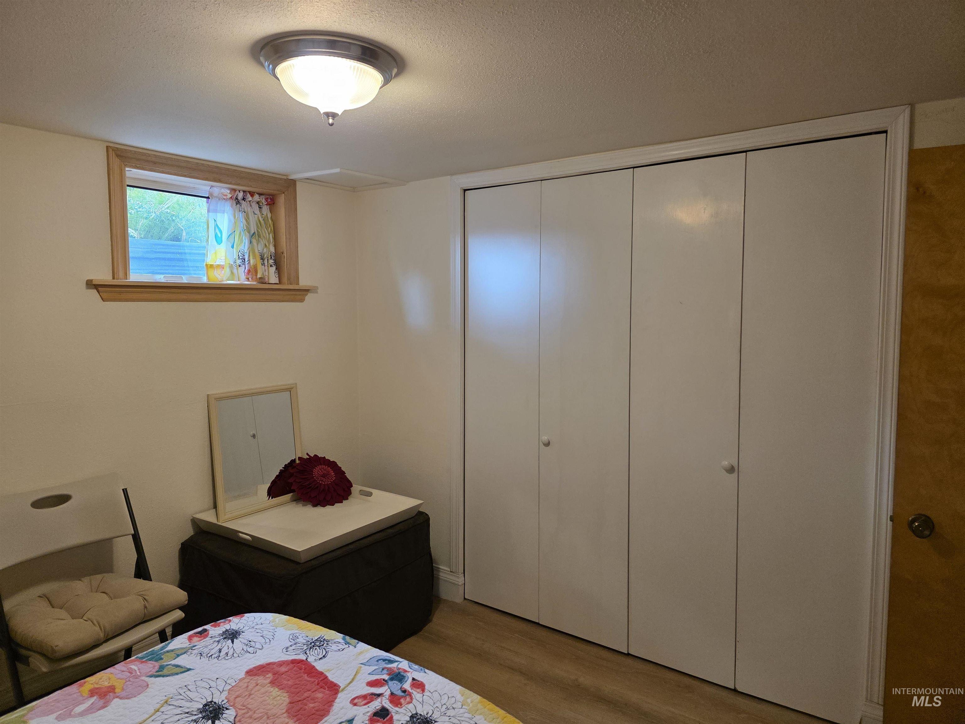Bedroom featuring wood finished floors, a closet, and a textured ceiling