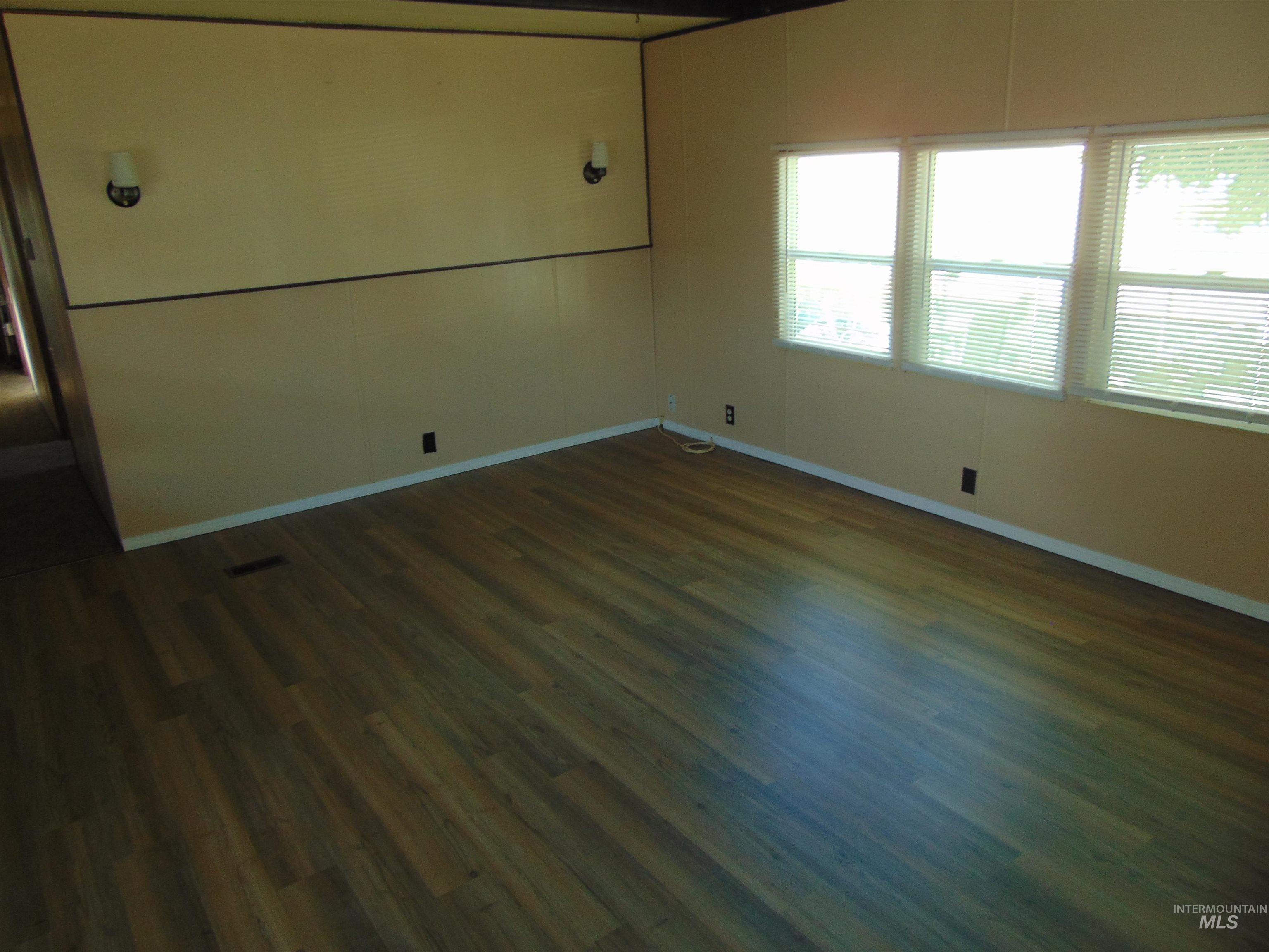 Spare room with dark wood-style floors and baseboards