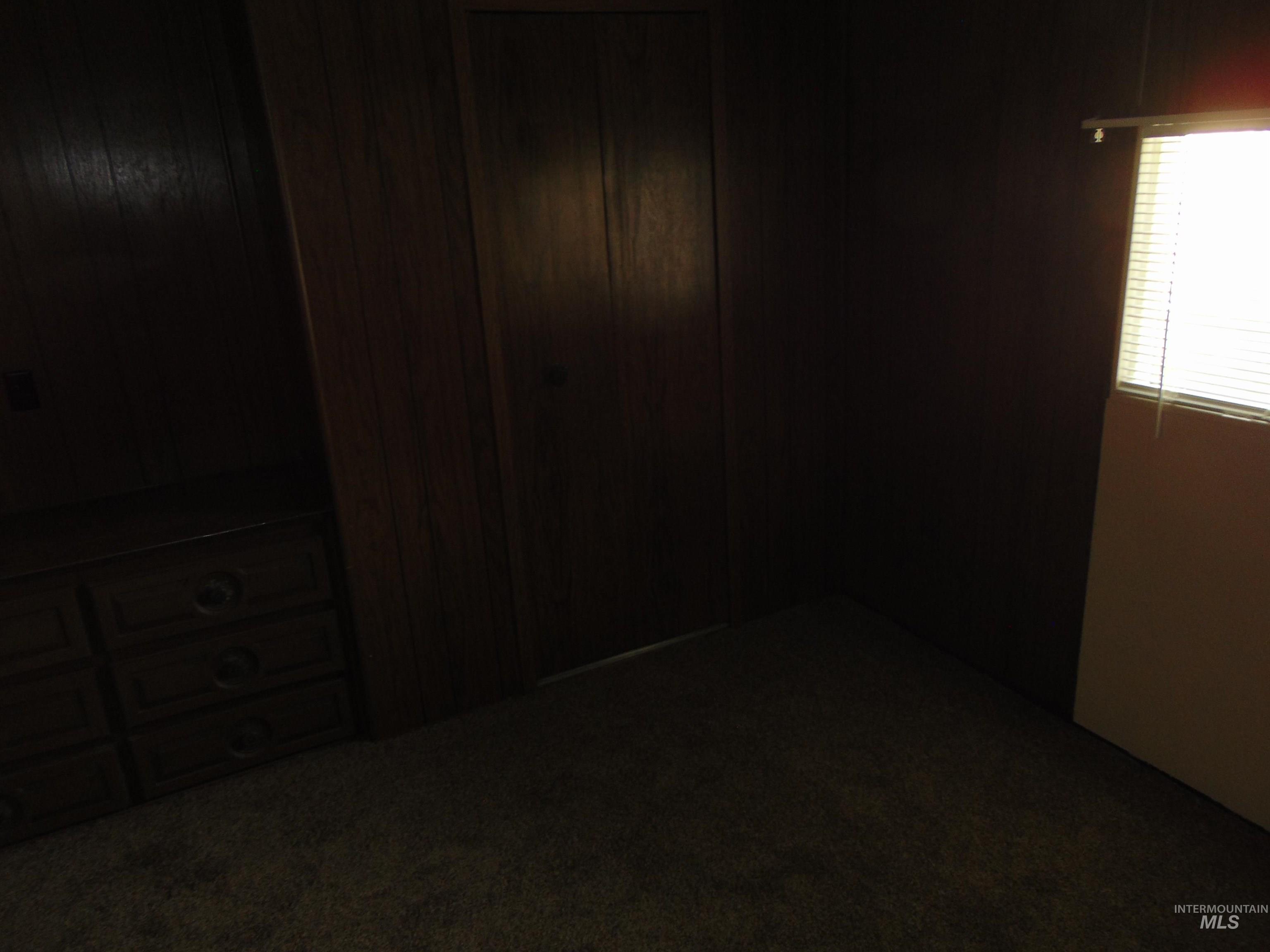 Unfurnished bedroom featuring dark carpet and wood walls