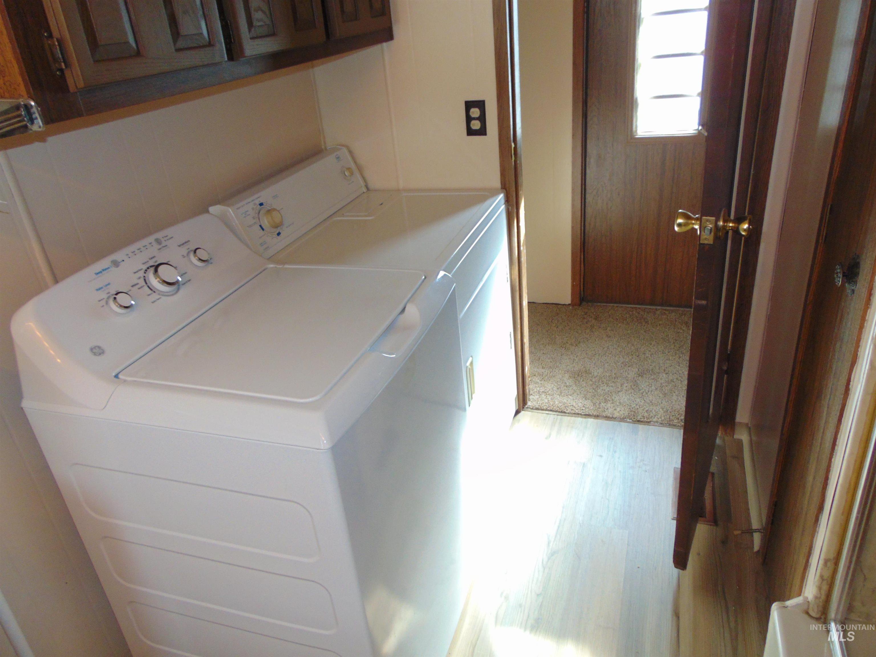 Laundry room with washer and dryer and light wood-style floors