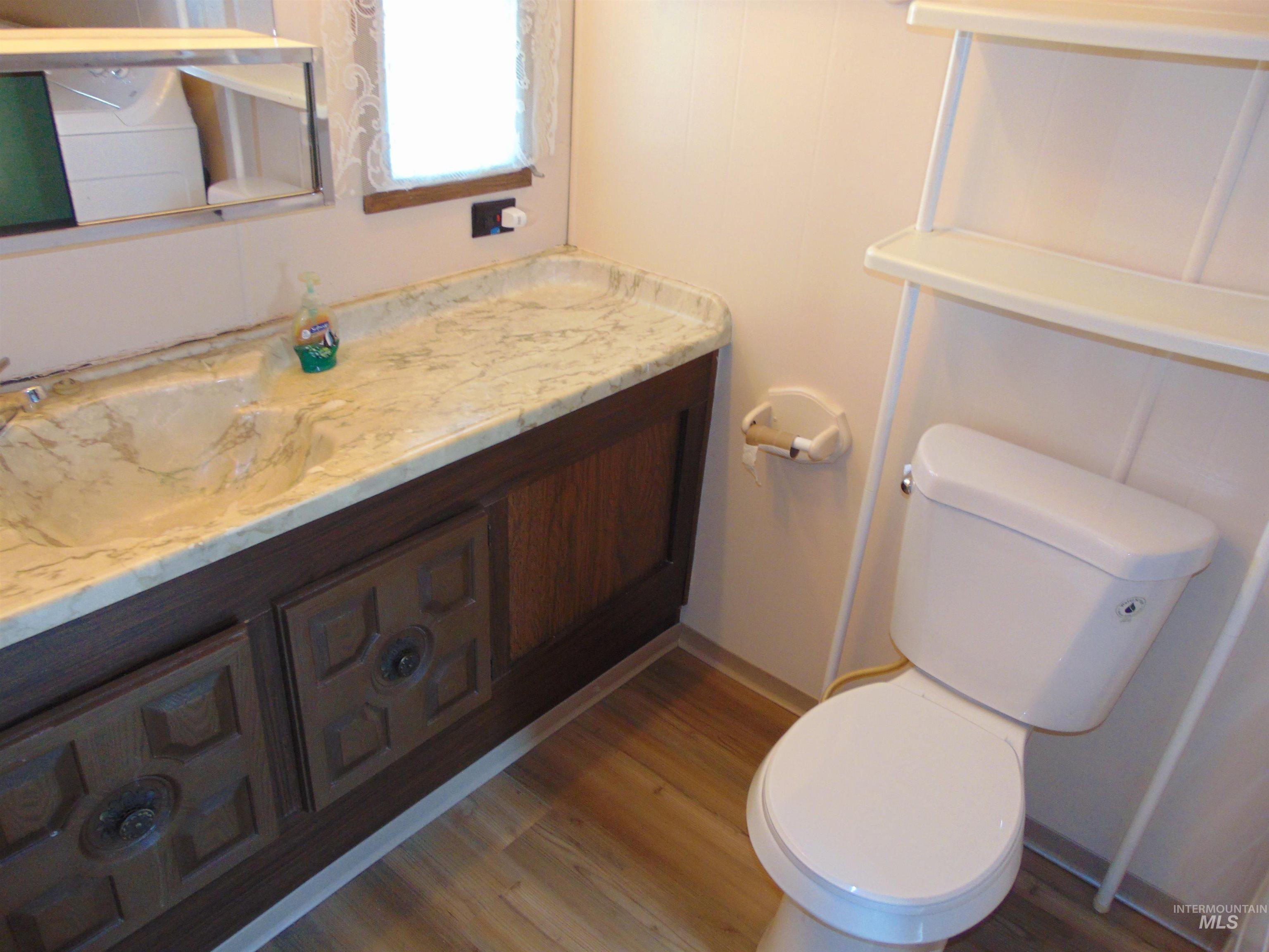 Bathroom featuring vanity, light wood-type flooring, and a decorative wall