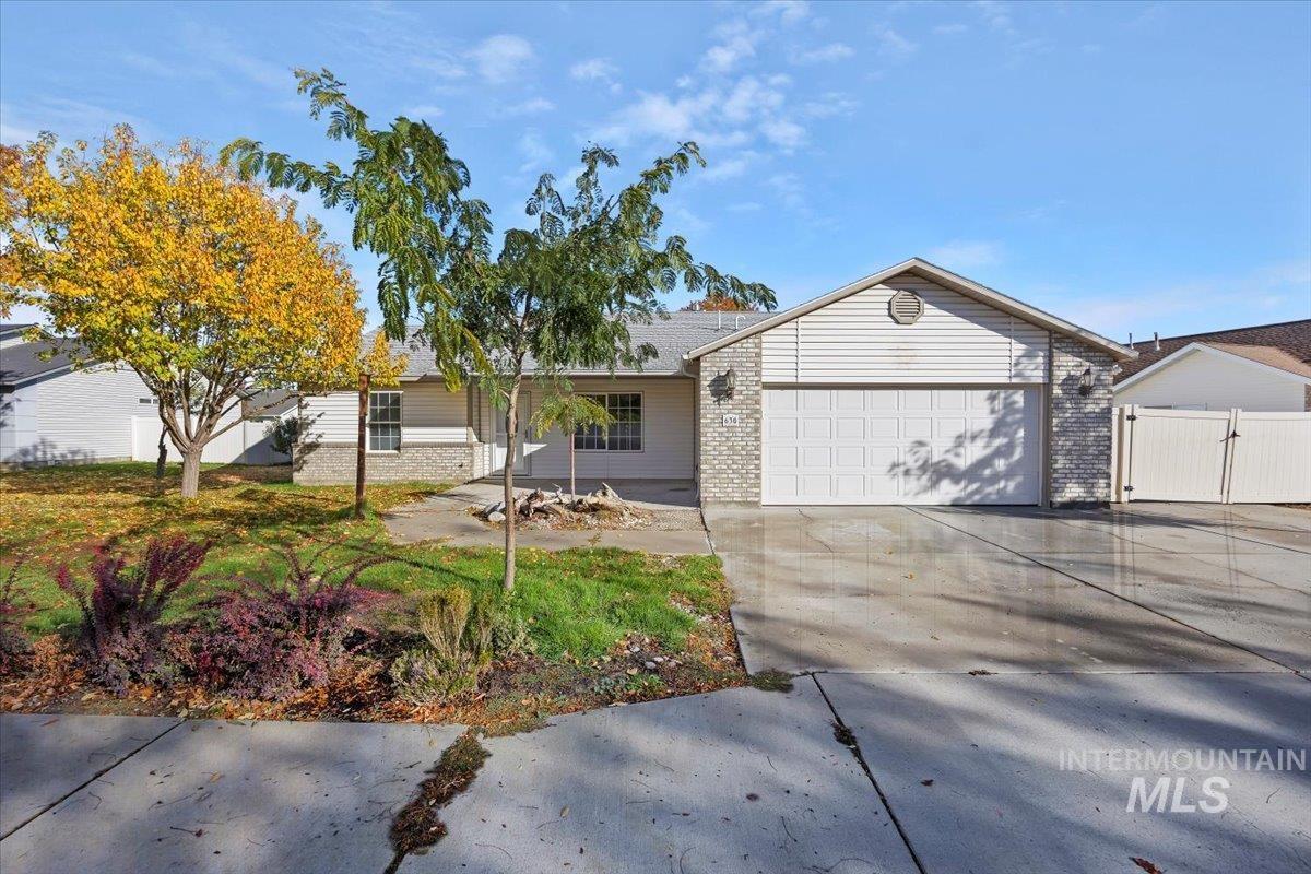 Single story home featuring brick siding, concrete driveway, a garage, and a gate