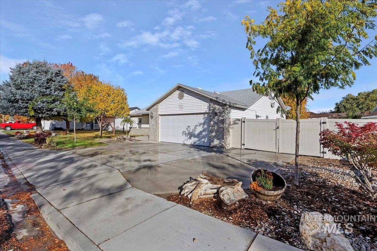 View of side of home featuring a gate, concrete driveway, a garage, and brick siding