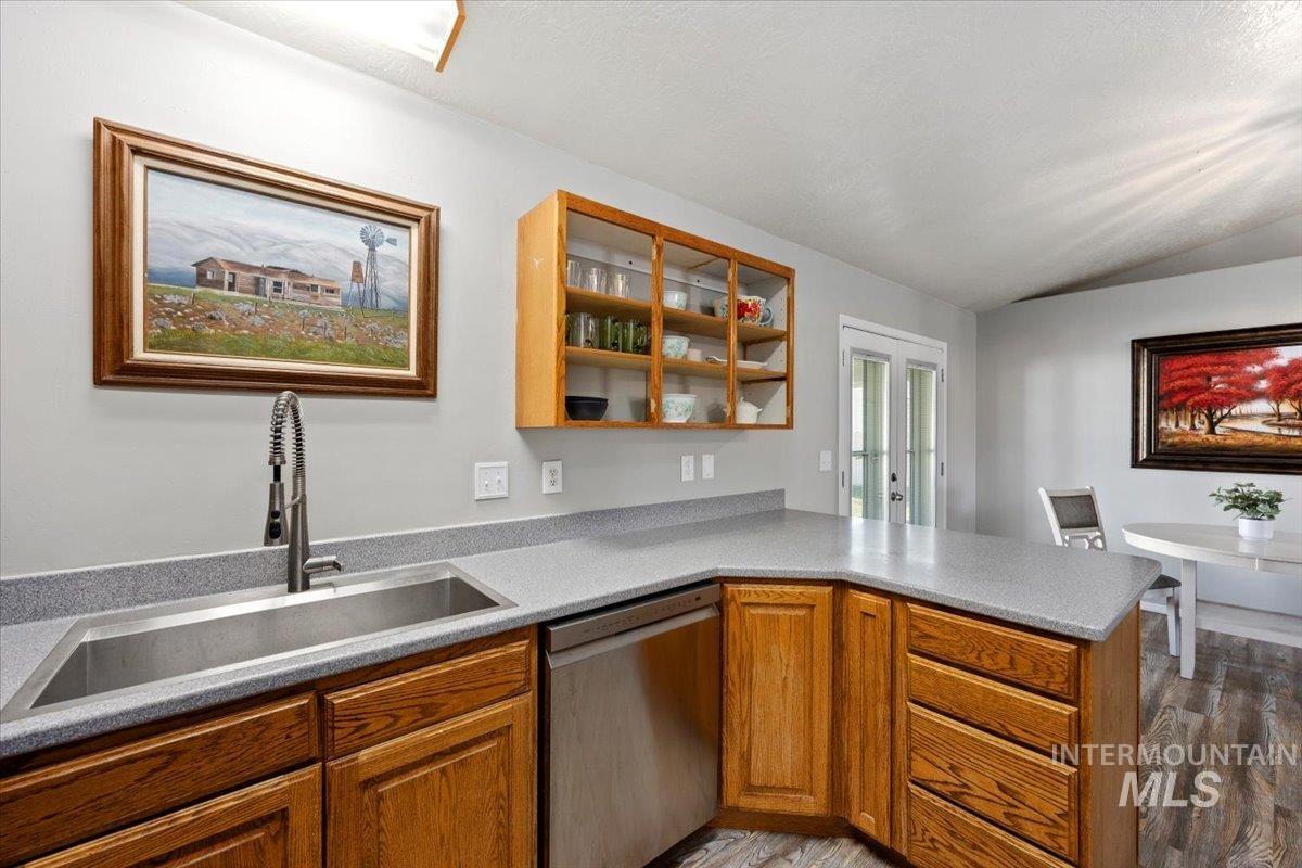 Kitchen featuring dishwasher, glass insert cabinets, a peninsula, brown cabinets, and open shelves