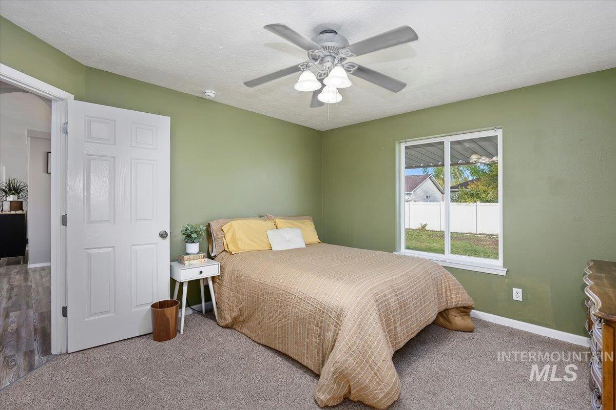 Bedroom with a textured ceiling, carpet flooring, and a ceiling fan