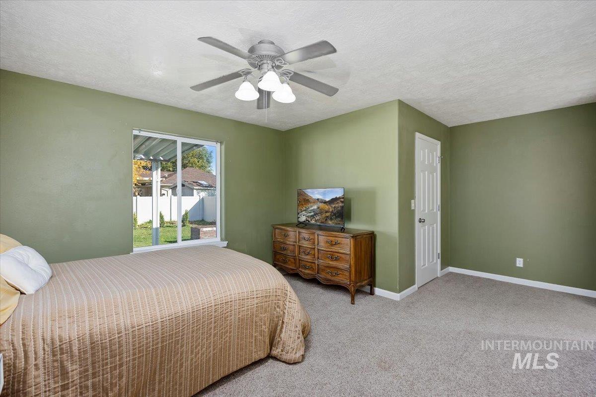 Bedroom with carpet flooring, a textured ceiling, and a ceiling fan