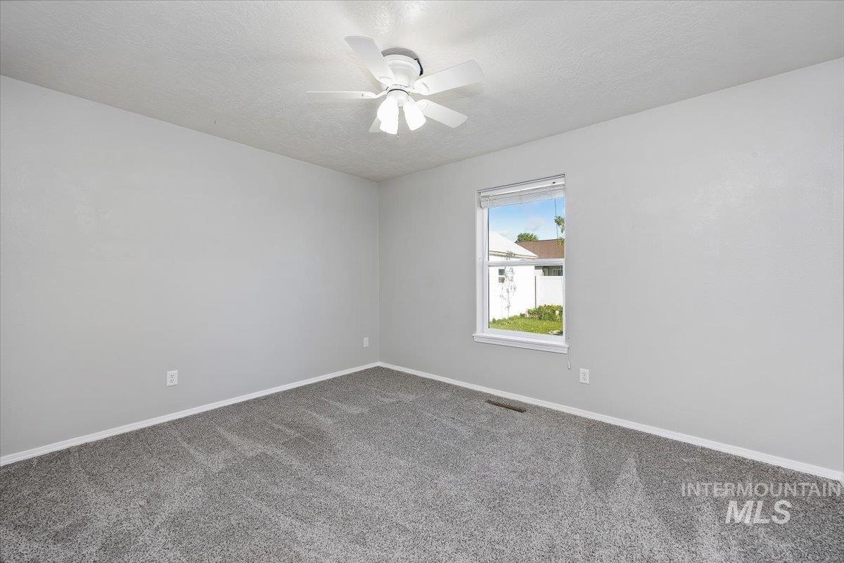 Carpeted spare room with a textured ceiling and a ceiling fan