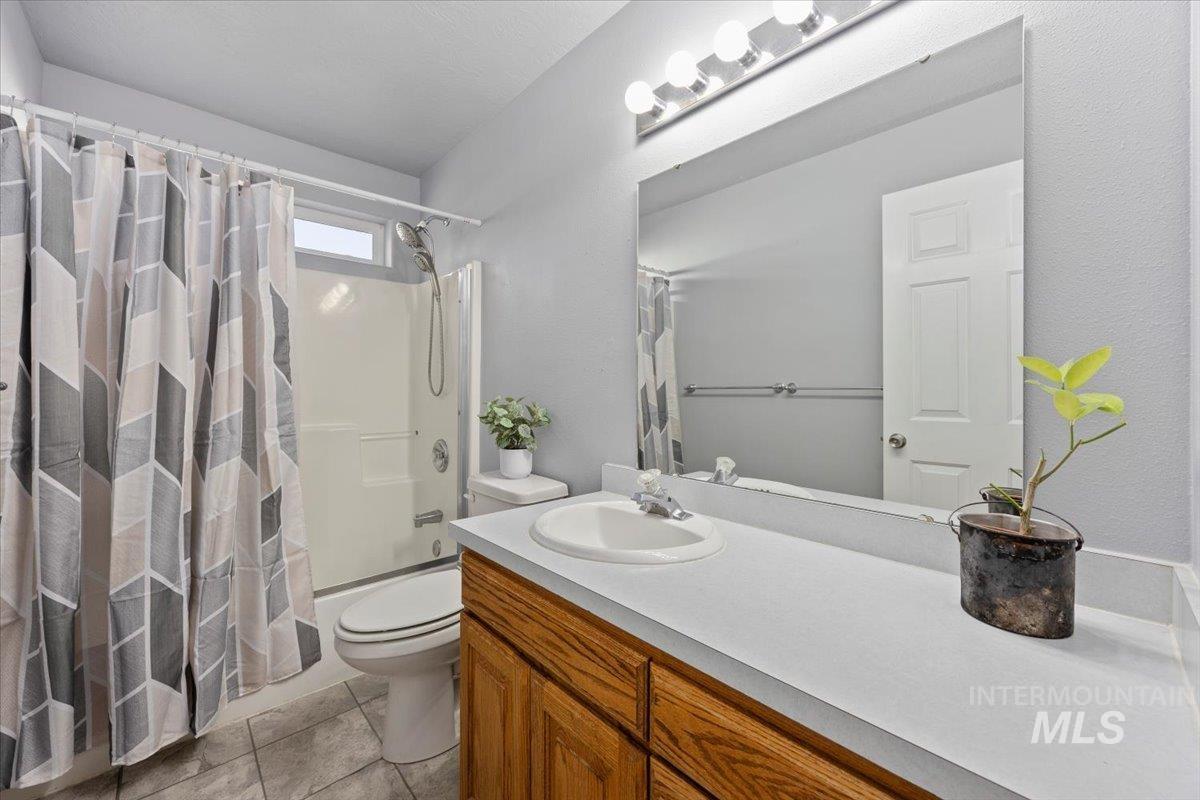 Full bath featuring shower / tub combo, vanity, and light tile patterned floors
