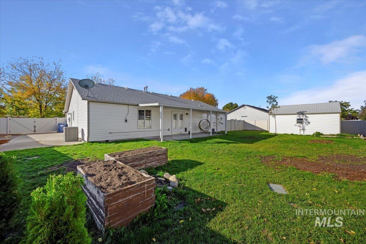 Rear view of property featuring a patio area, a fenced backyard, a gate, and a garden
