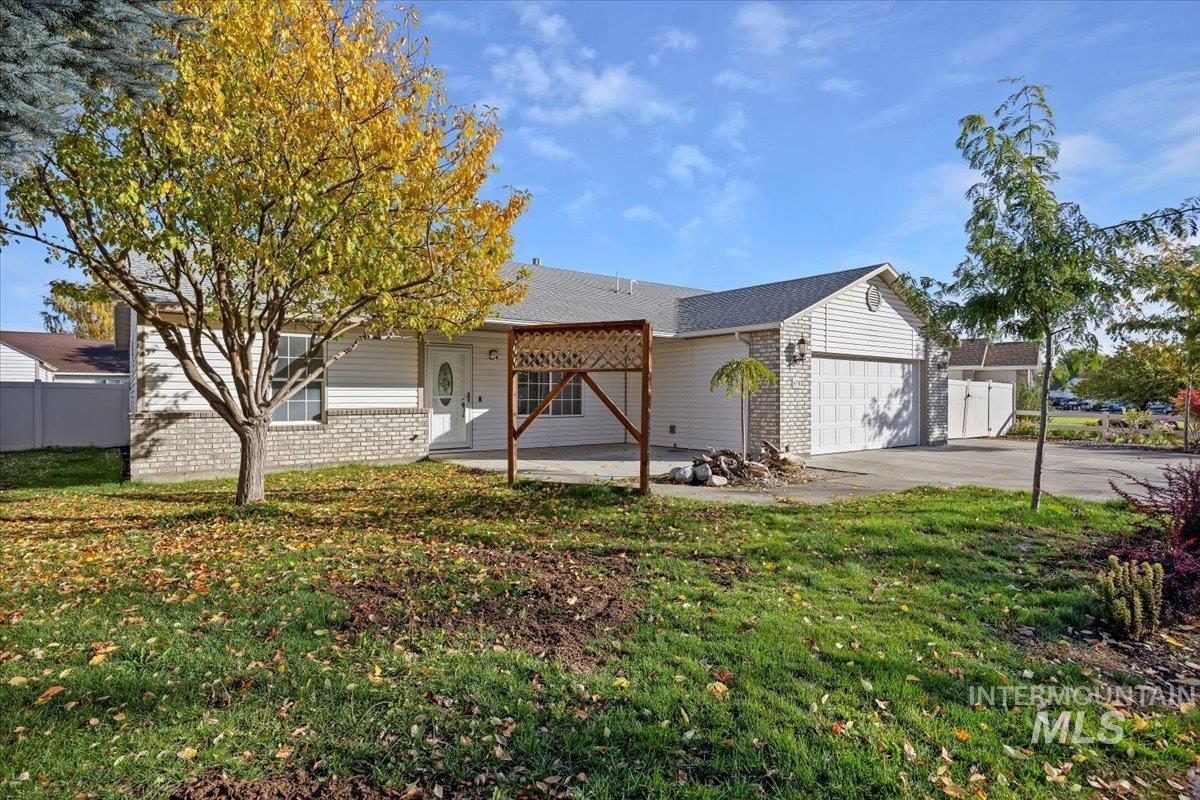 Ranch-style home featuring brick siding, driveway, an attached garage, and a patio