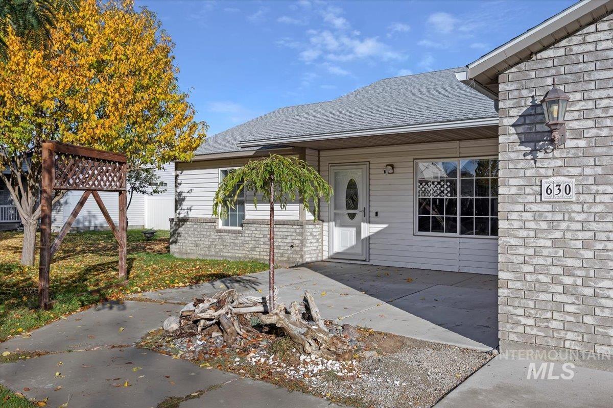 View of exterior entry with a shingled roof and brick siding