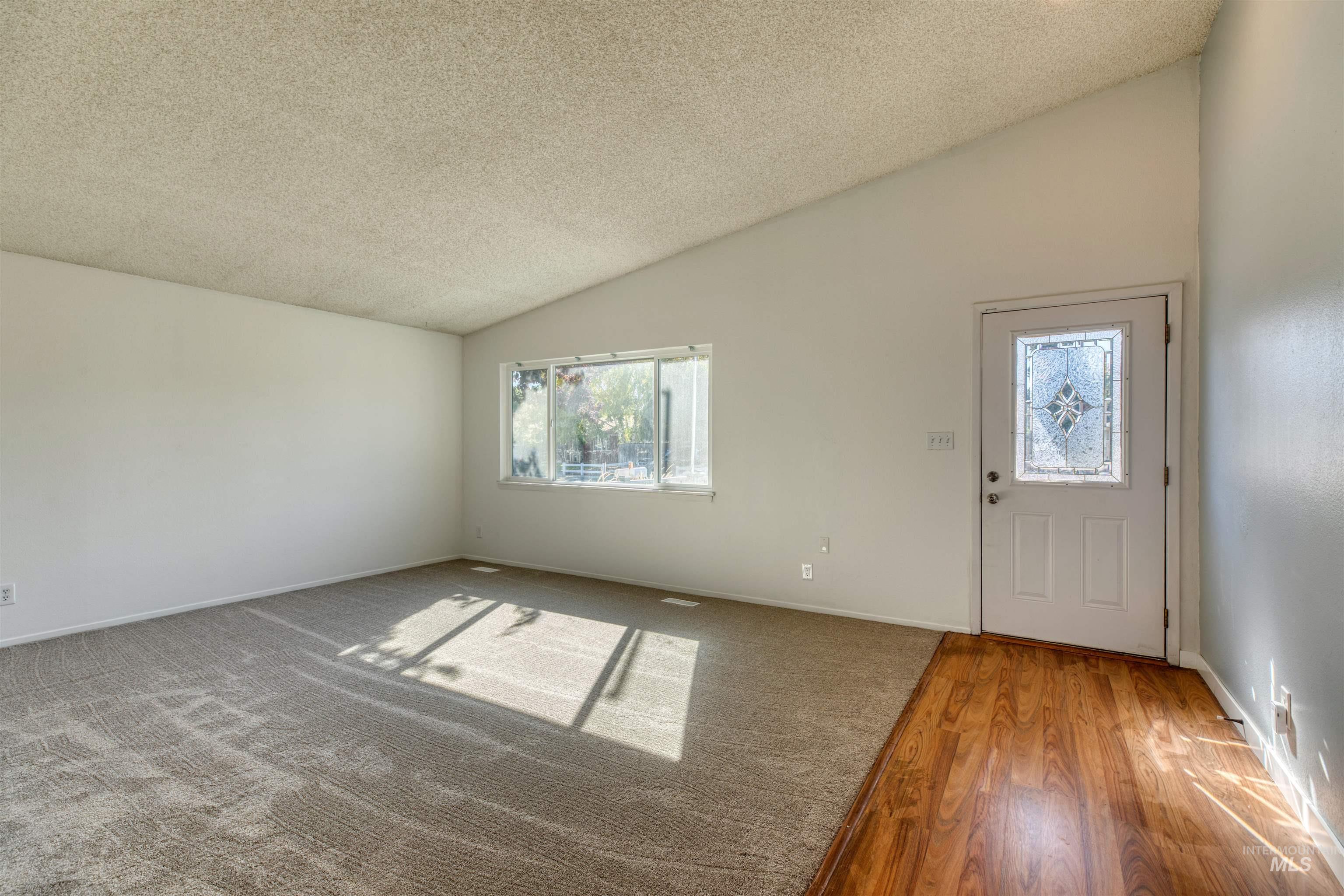 Entryway featuring lofted ceiling, a textured ceiling, and wood finished floors