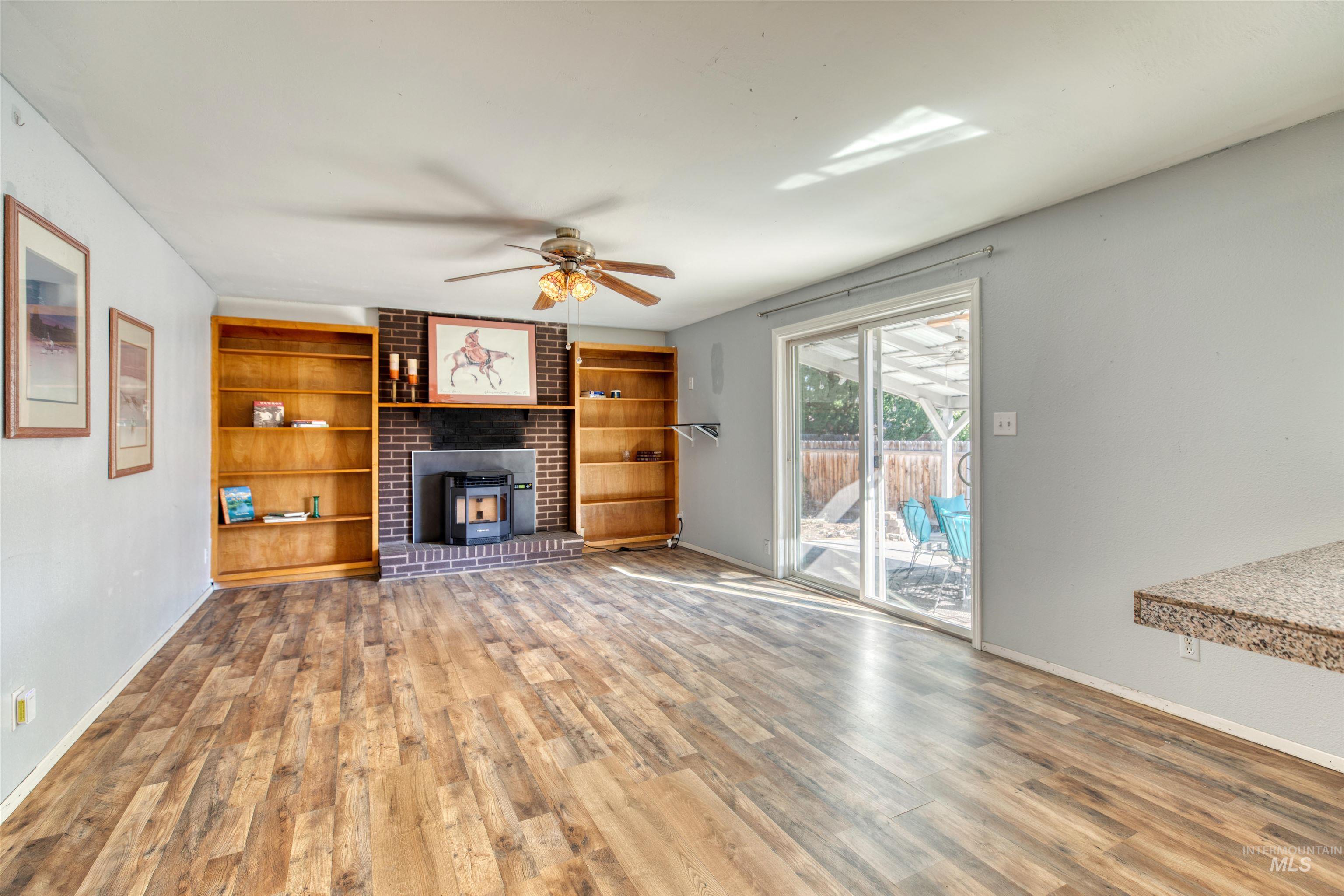 Unfurnished living room with wood finished floors, built in shelves, and ceiling fan