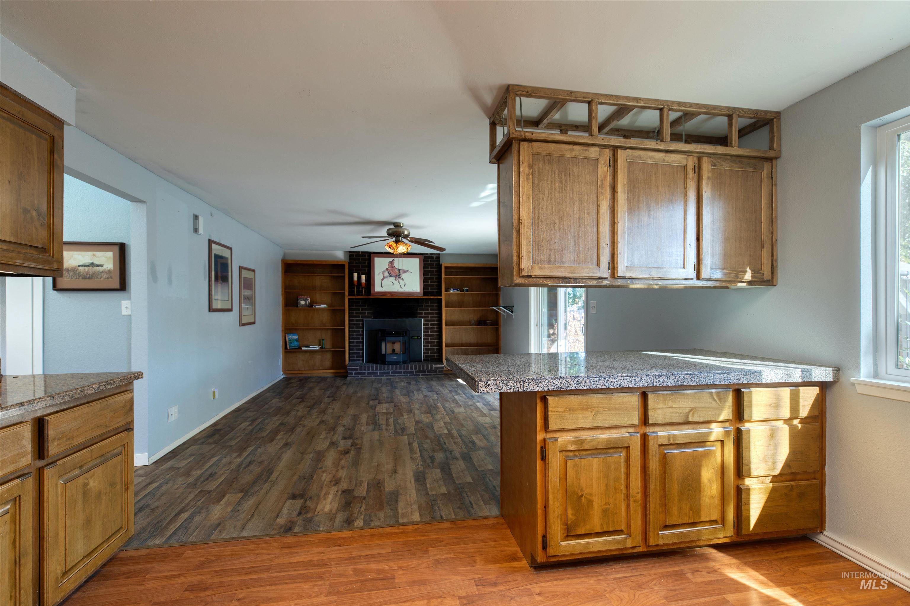 Kitchen with brown cabinetry, dark wood finished floors, a peninsula, and ceiling fan