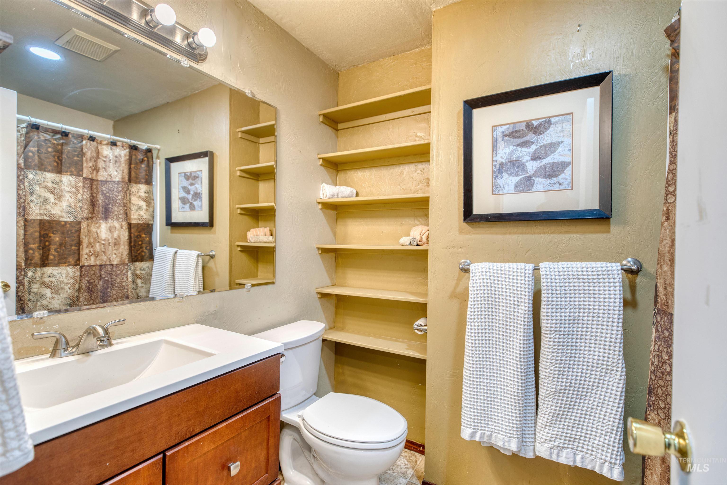 Full bathroom with vanity, a shower with shower curtain, and a textured wall