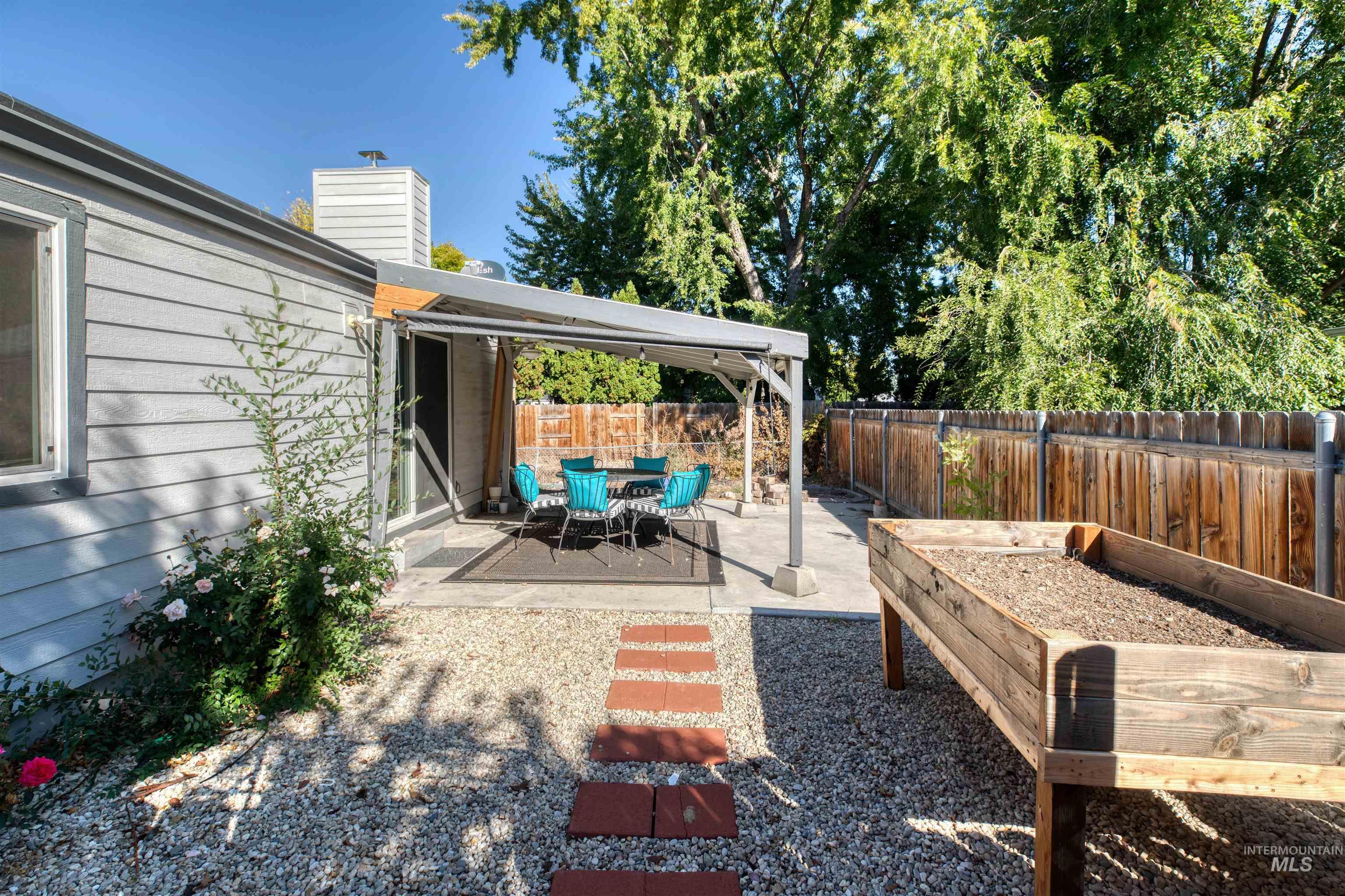Fenced backyard featuring a patio area and a vegetable garden