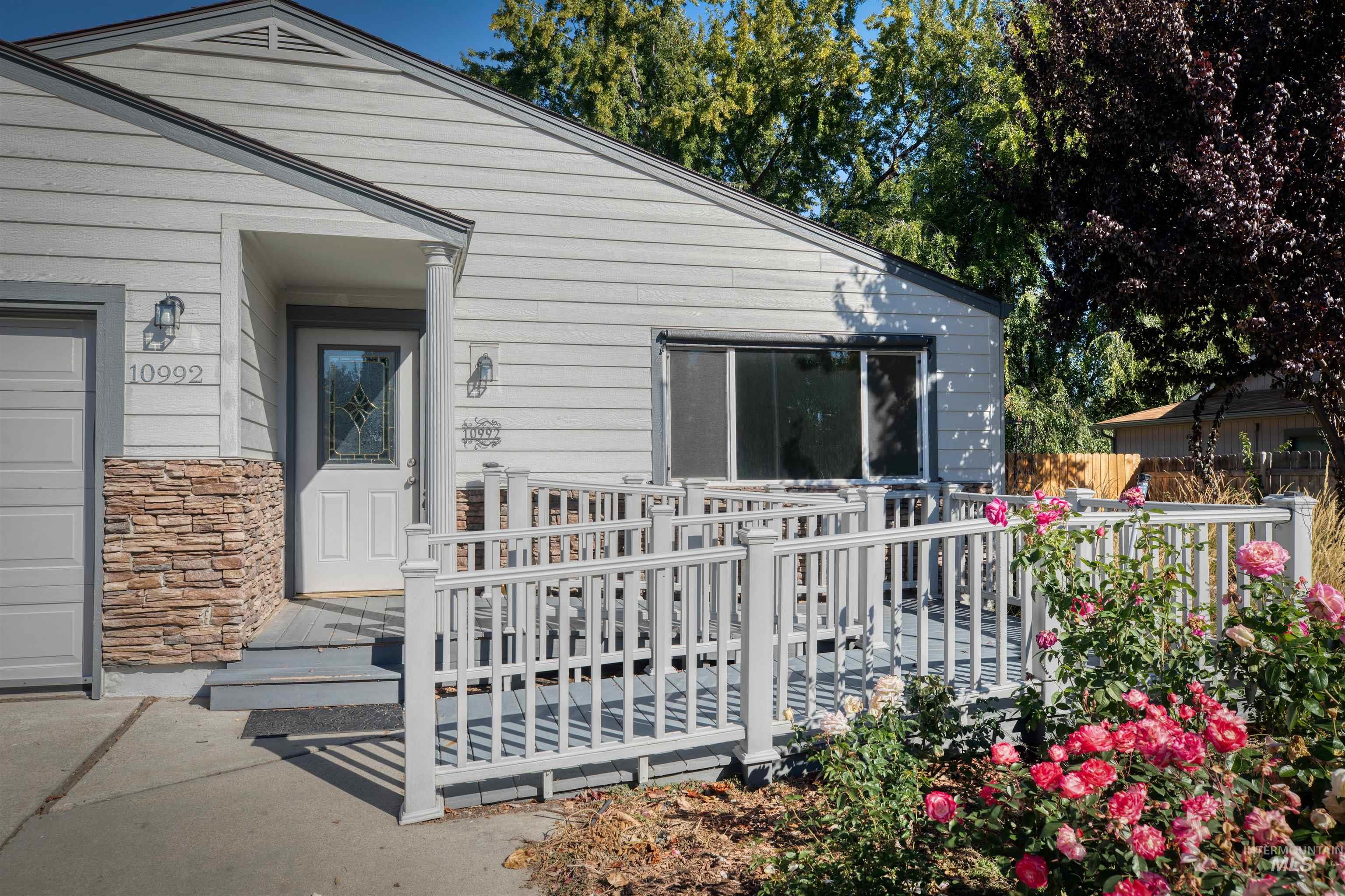 Doorway to property with stone siding, a wooden deck, and a garage