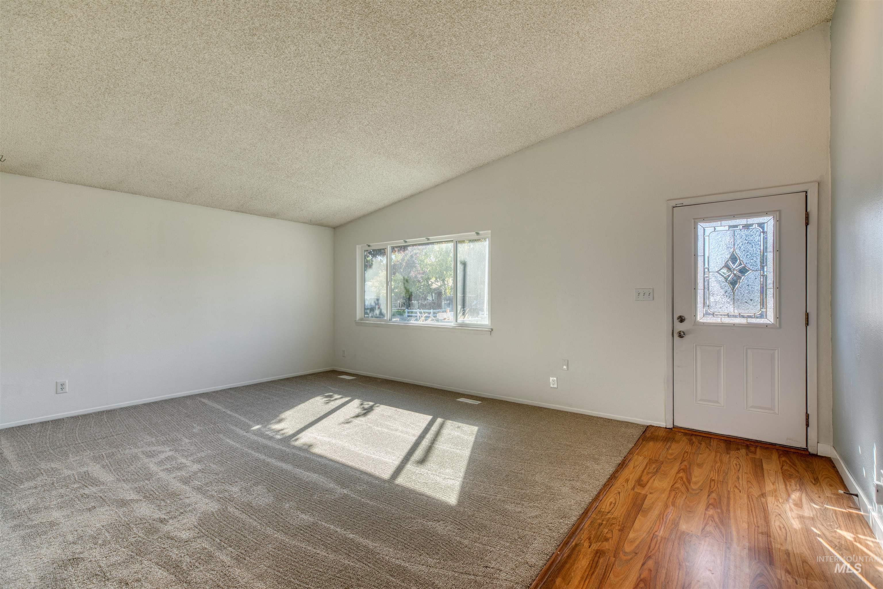 Entryway featuring vaulted ceiling, a textured ceiling, wood finished floors, and carpet