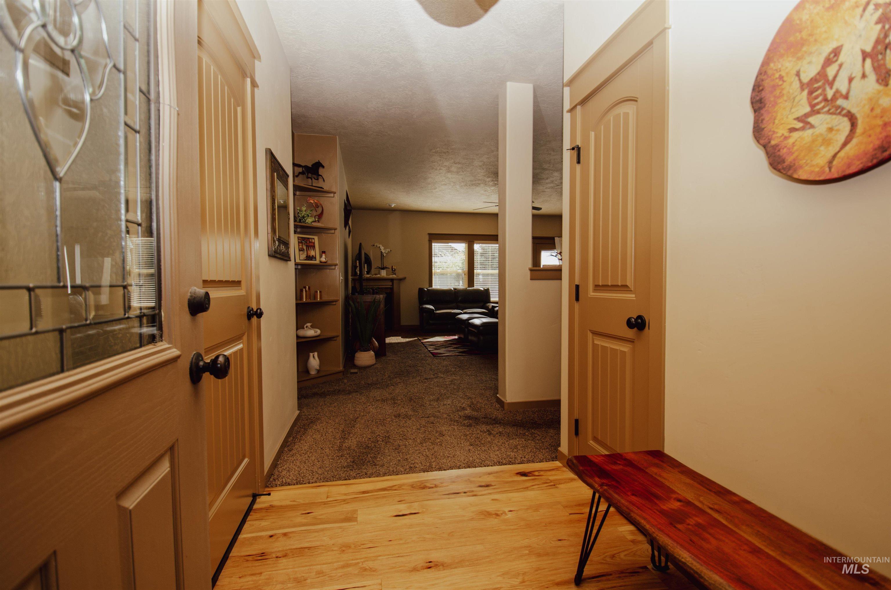 Corridor featuring light wood-style floors, a textured ceiling, and light carpet