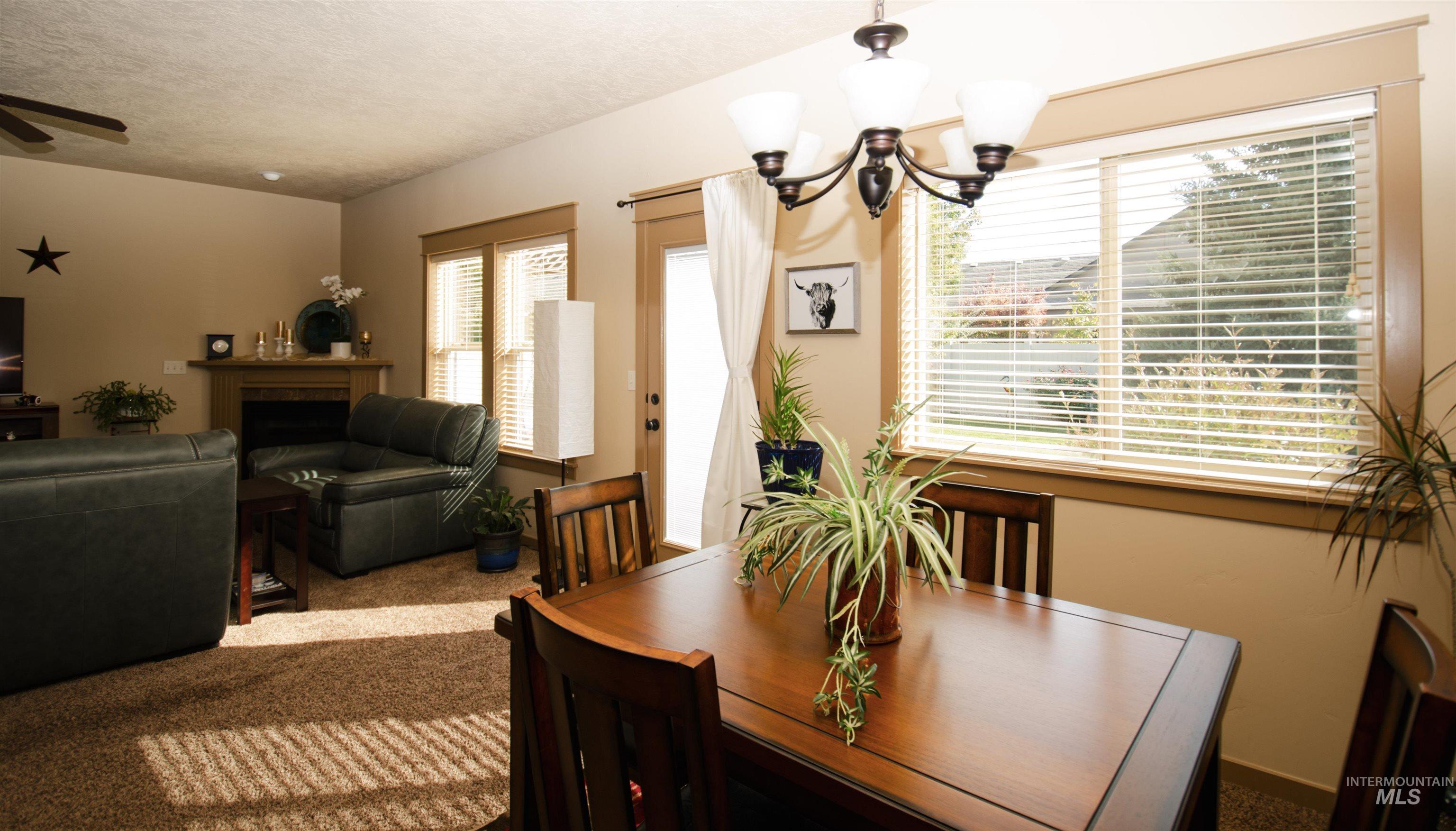 Carpeted dining space with a chandelier, a fireplace, and a textured ceiling