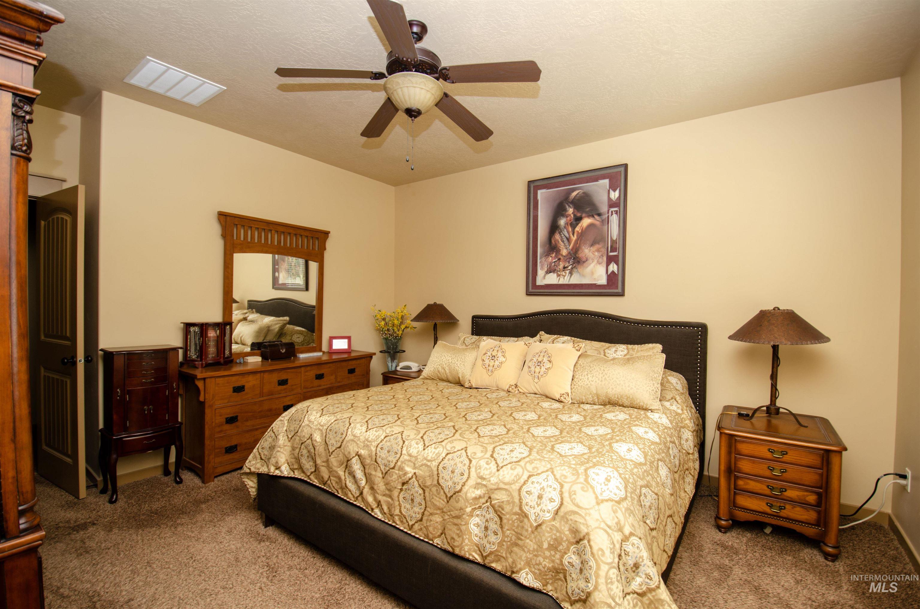 Carpeted bedroom featuring a textured ceiling and ceiling fan